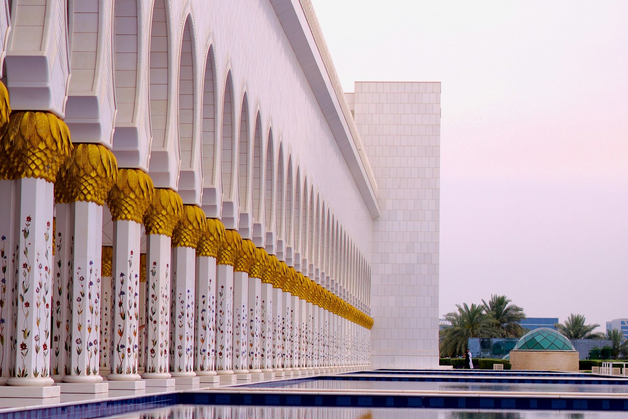 Gilded columns and arches reflected in the pools of the Sheikh Zayed Grand Mosque