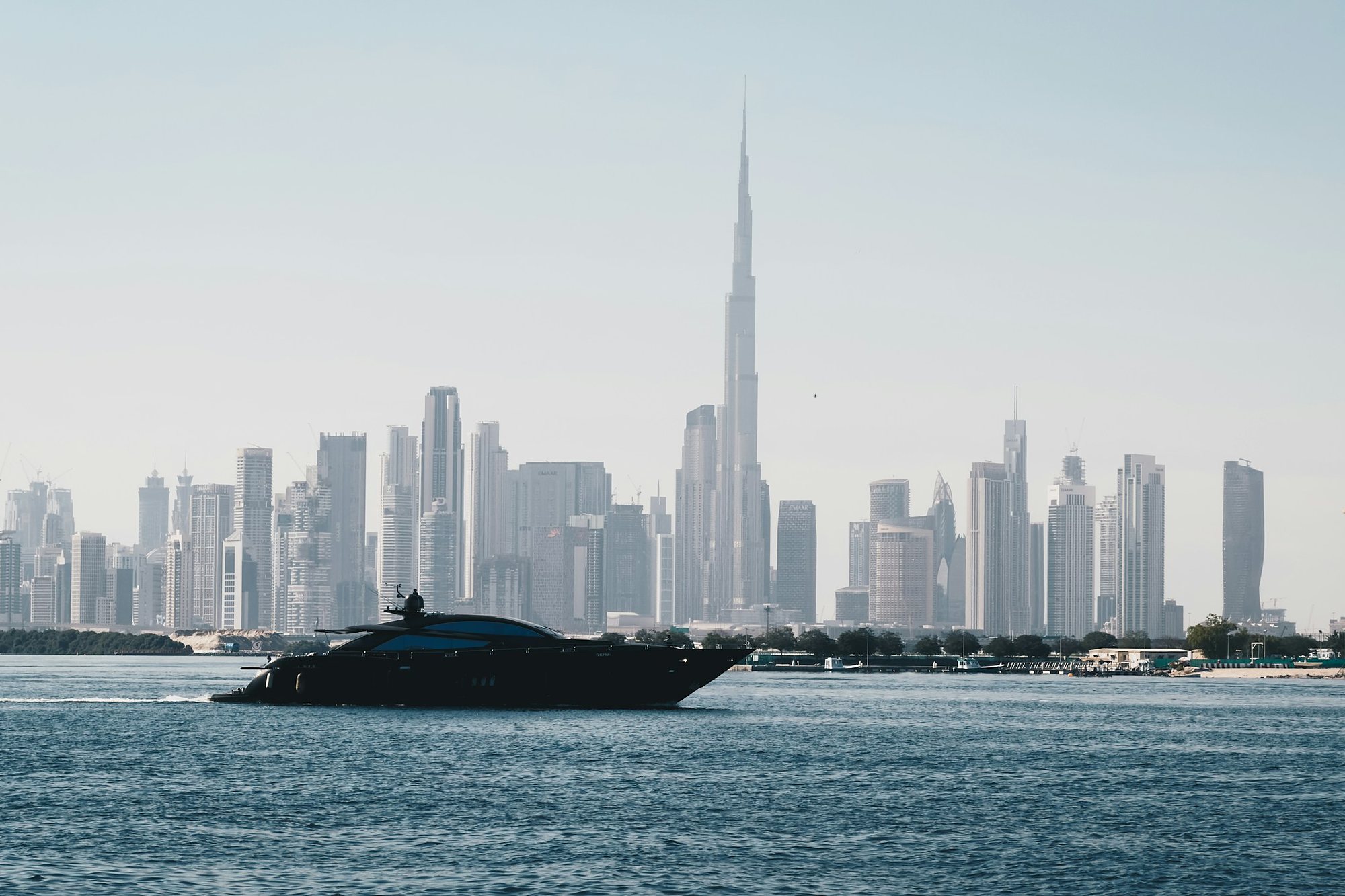 A motor yacht crossing the water in front of the Dubai skyline