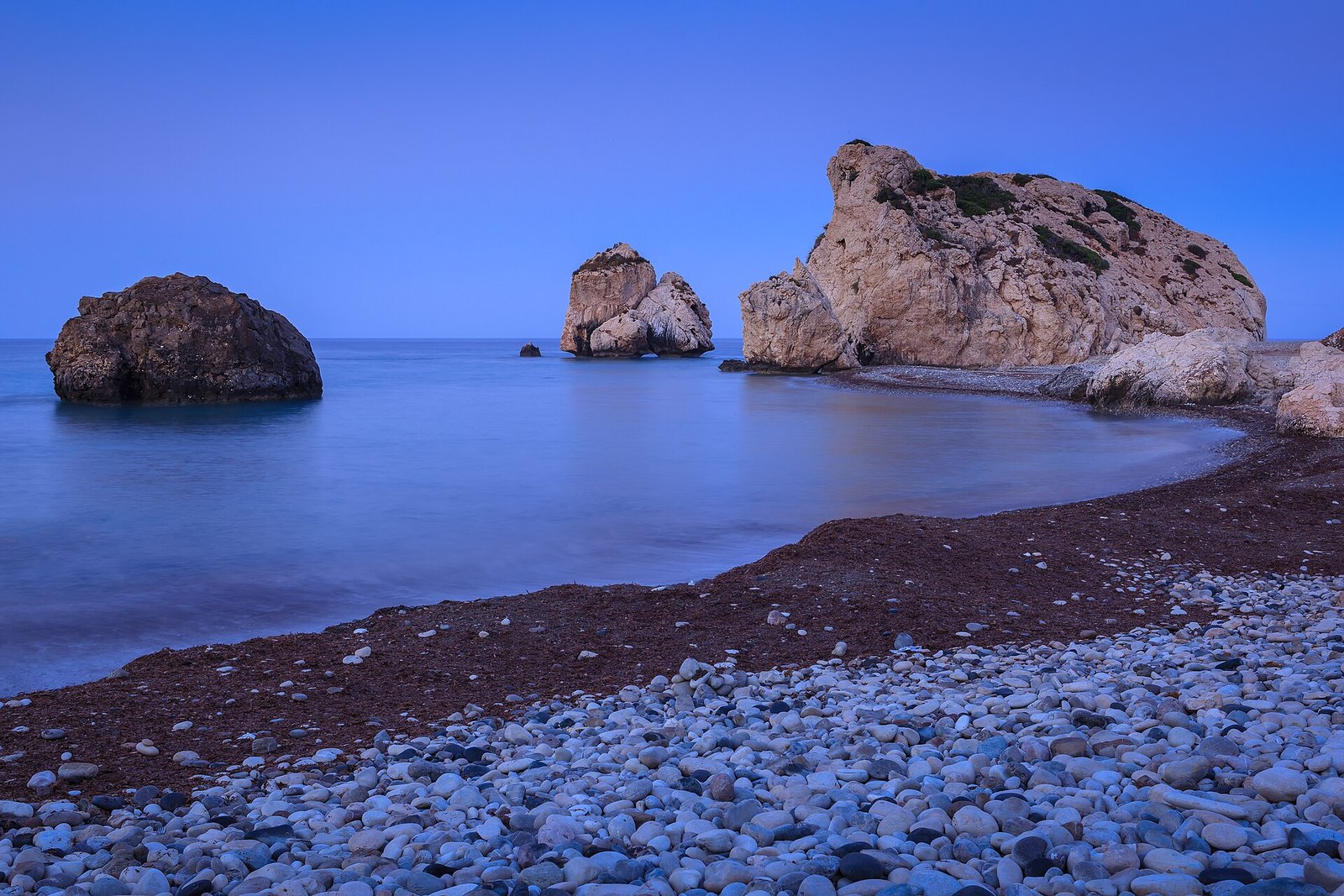 Petra tou Romiou, Aphrodite's Rock, rising from a calm sea in the blue hour before sunrise on the Paphos coast of Cyprus.