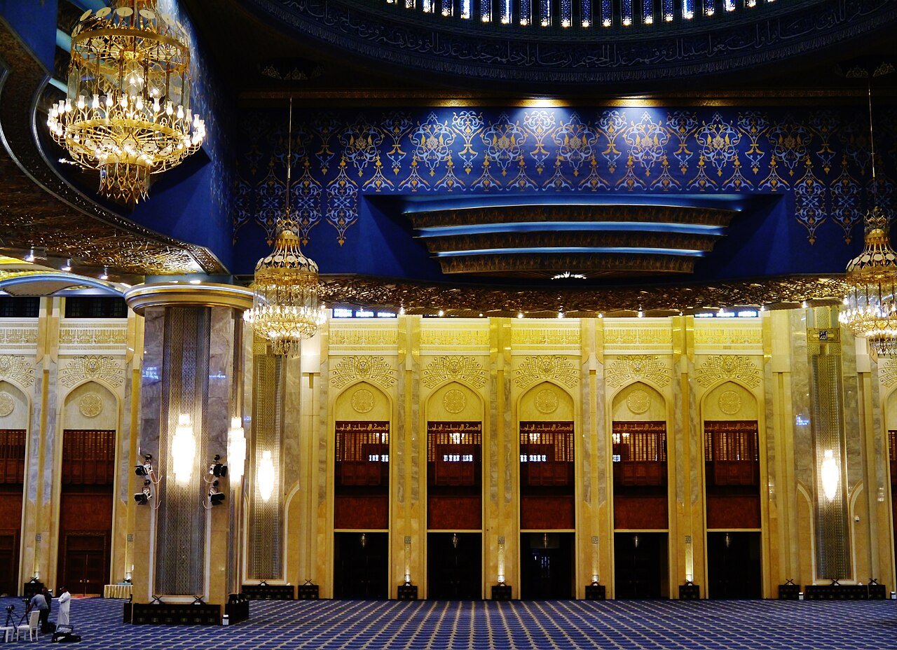 The gilded columns, chandeliers and carved wooden doors of the main prayer hall of the Grand Mosque, Kuwait City.