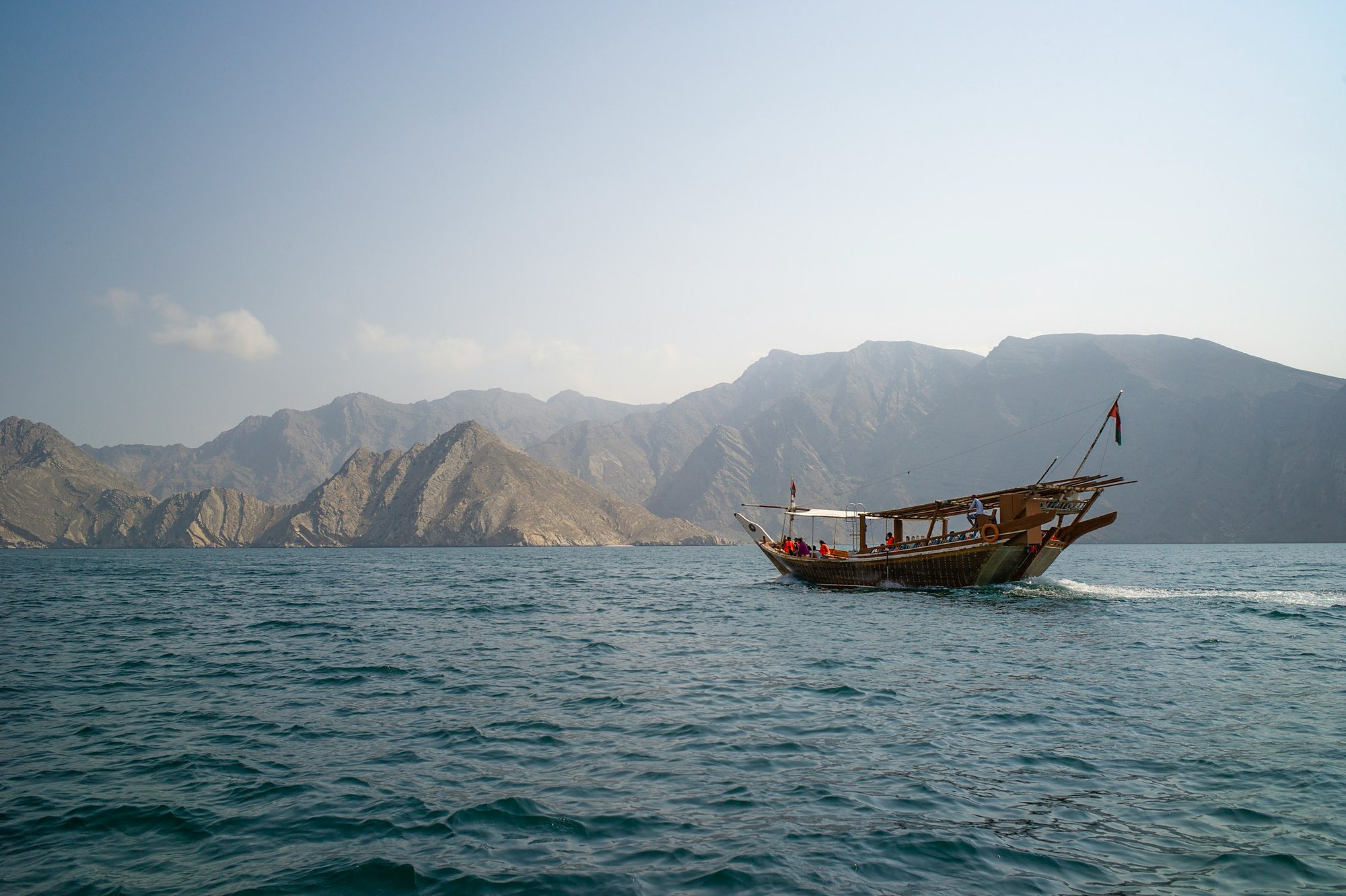 A traditional dhow crossing the fjords of Musandam below the mountains