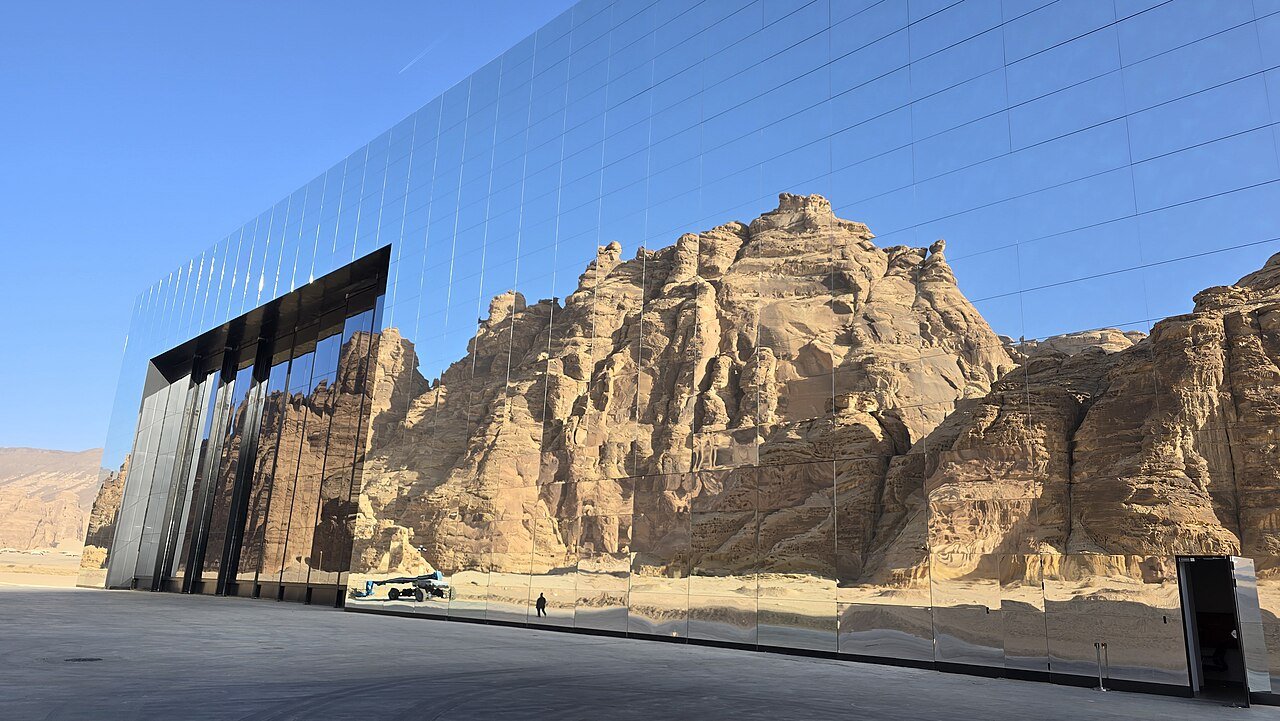 The sandstone cliffs of AlUla reflected in the mirrored facade of Maraya, the desert concert hall.