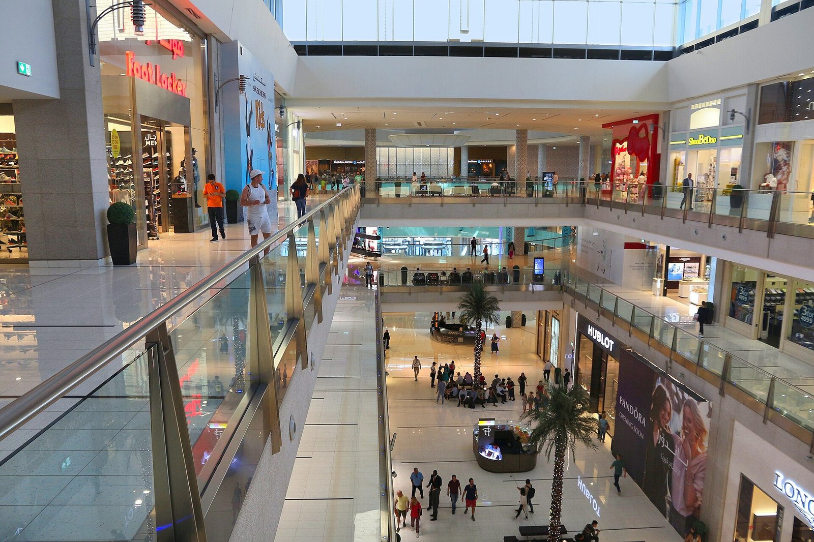 Palm trees rise through the glass-railed, multi-level atrium of The Dubai Mall.