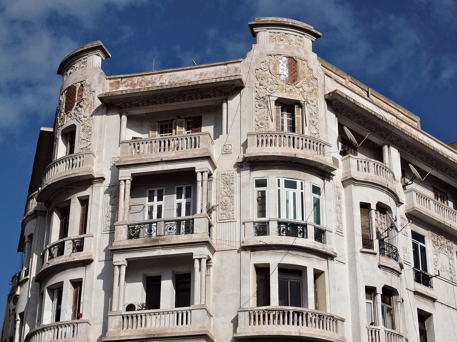 An ornate white Art Deco apartment building with sculpted balconies under a blue sky in central Casablanca.