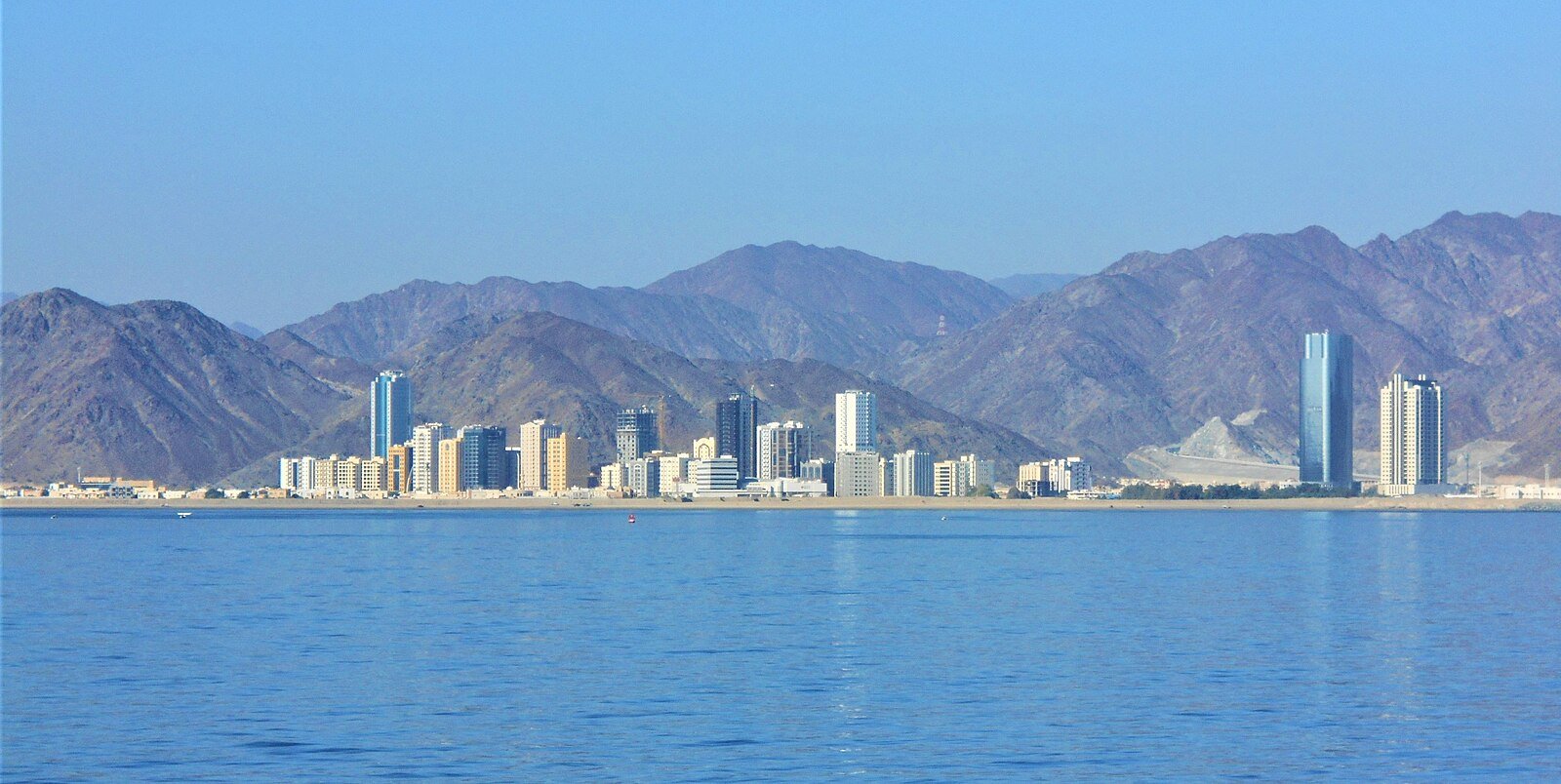 The towers of Fujairah City lining the Gulf of Oman beneath the rugged Hajar Mountains