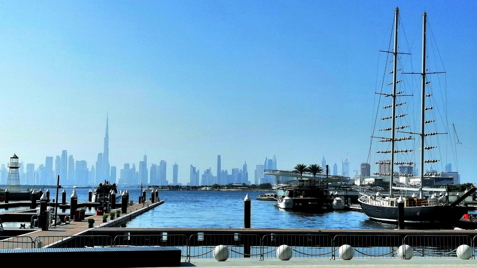 A tall-masted schooner moored at the Dubai Creek Harbour marina, with the Downtown Dubai skyline across the water.