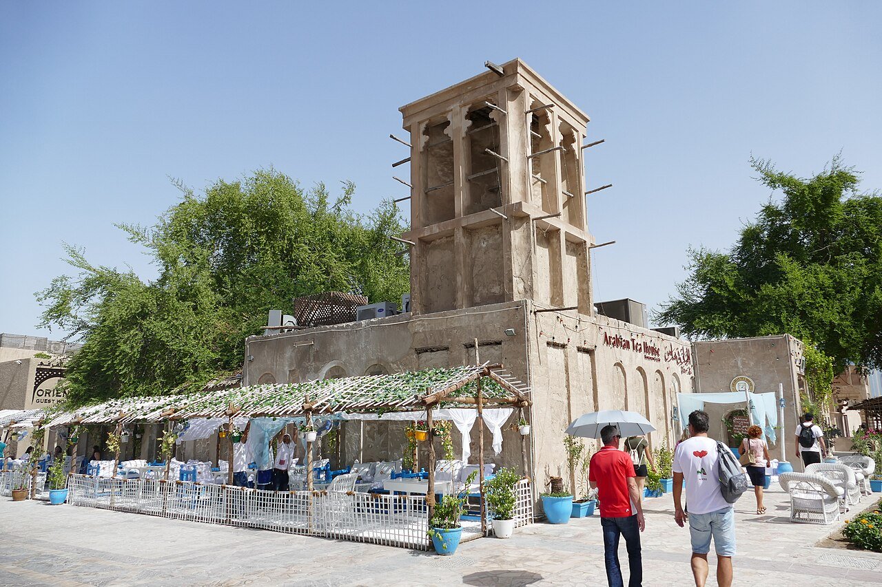 A wind tower rising above a shaded courtyard cafe in the Al Fahidi Historical Neighbourhood of old Dubai.