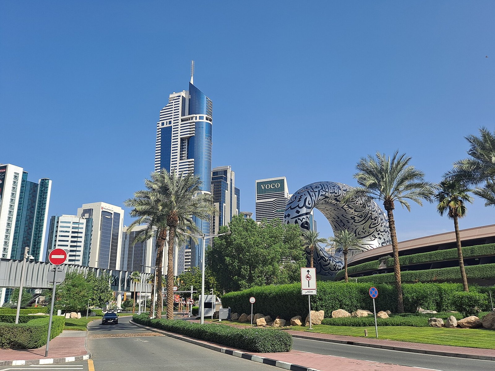 The silver, calligraphy-clad ring of the Museum of the Future among palms and towers on Sheikh Zayed Road, Dubai