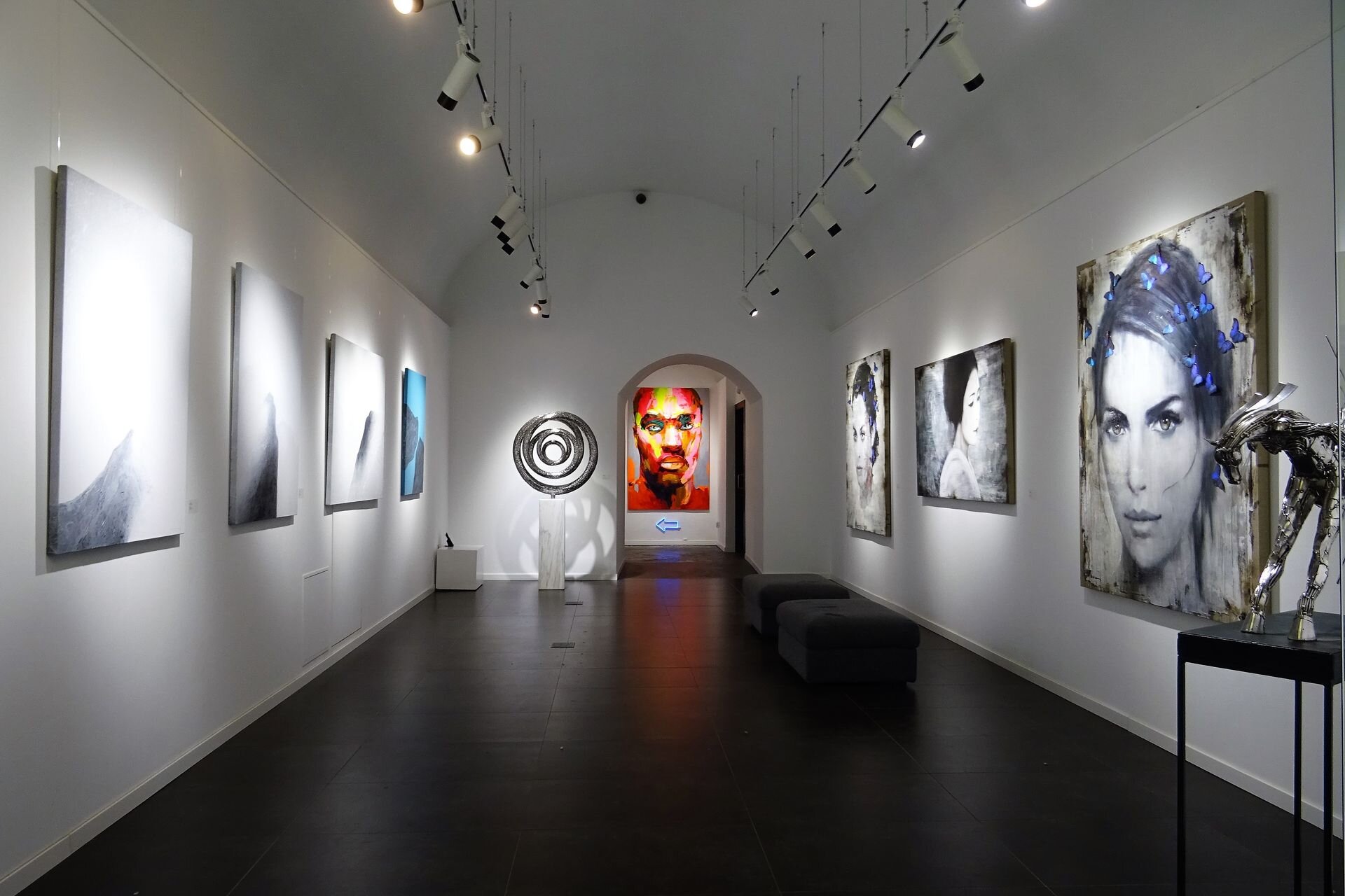 A vaulted contemporary art gallery with paintings and sculpture