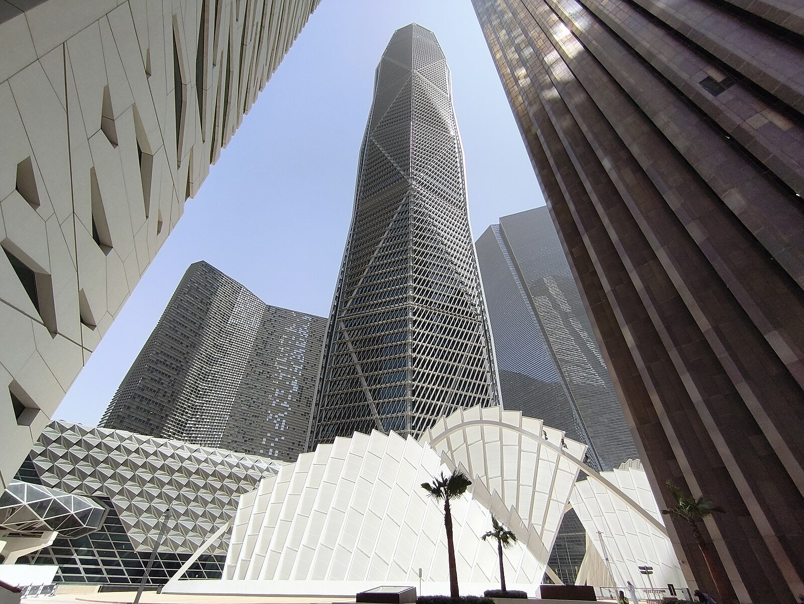 Faceted glass towers of the King Abdullah Financial District rising above sculpted white canopies and palms in Riyadh.