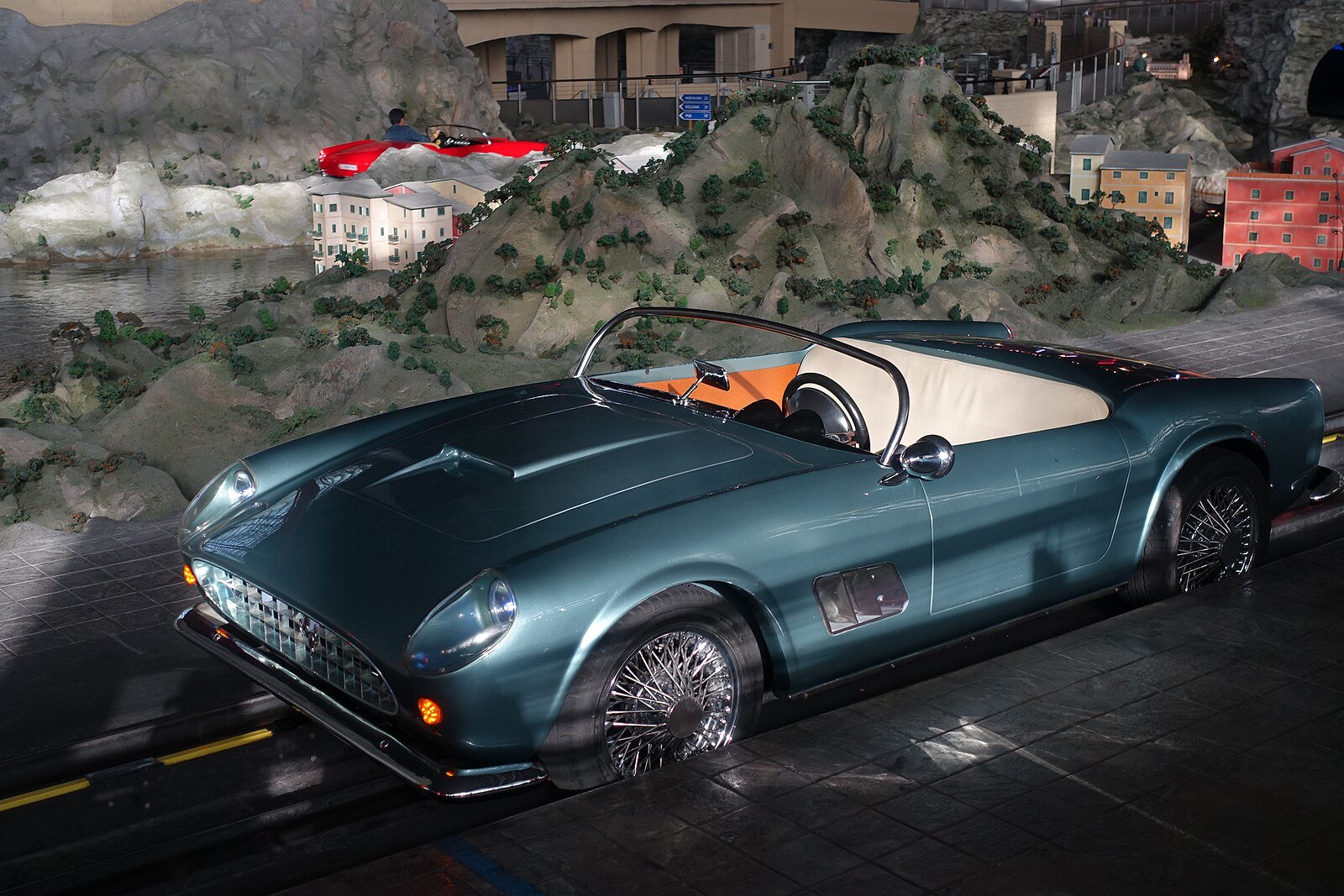 A vintage Ferrari 250 California Spyder on the Bell'Italia ride at Ferrari World, set against a miniature Italian coastline