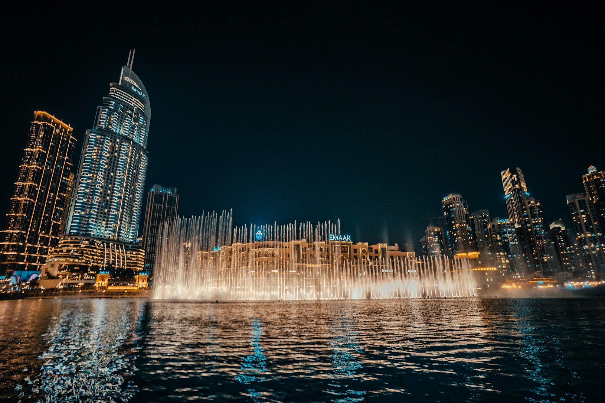 The Dubai Fountain lit gold at night beside Souk Al Bahar