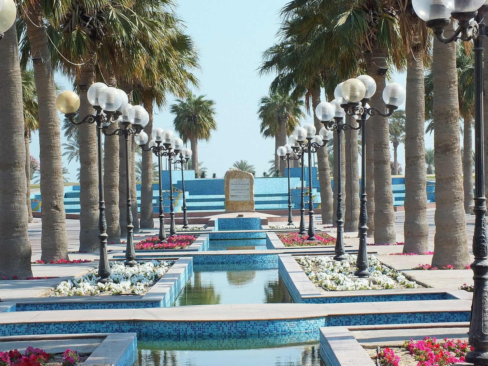 Palm-lined fountains and lanterns along the Al Khobar Corniche under a clear sky, Saudi Arabia.