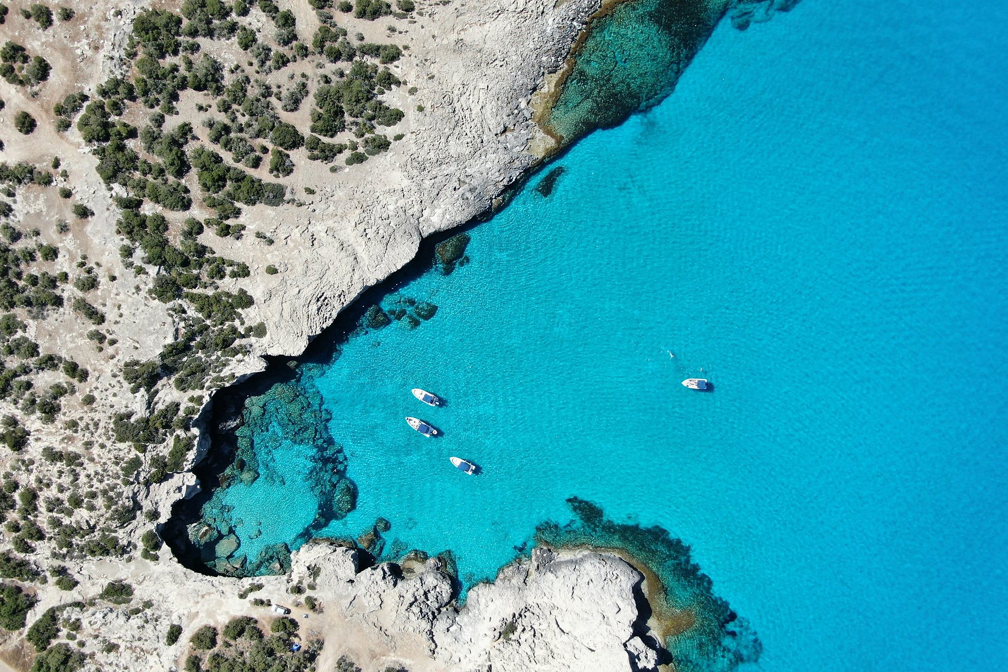 Boats in a turquoise cove on the Cyprus coast from above