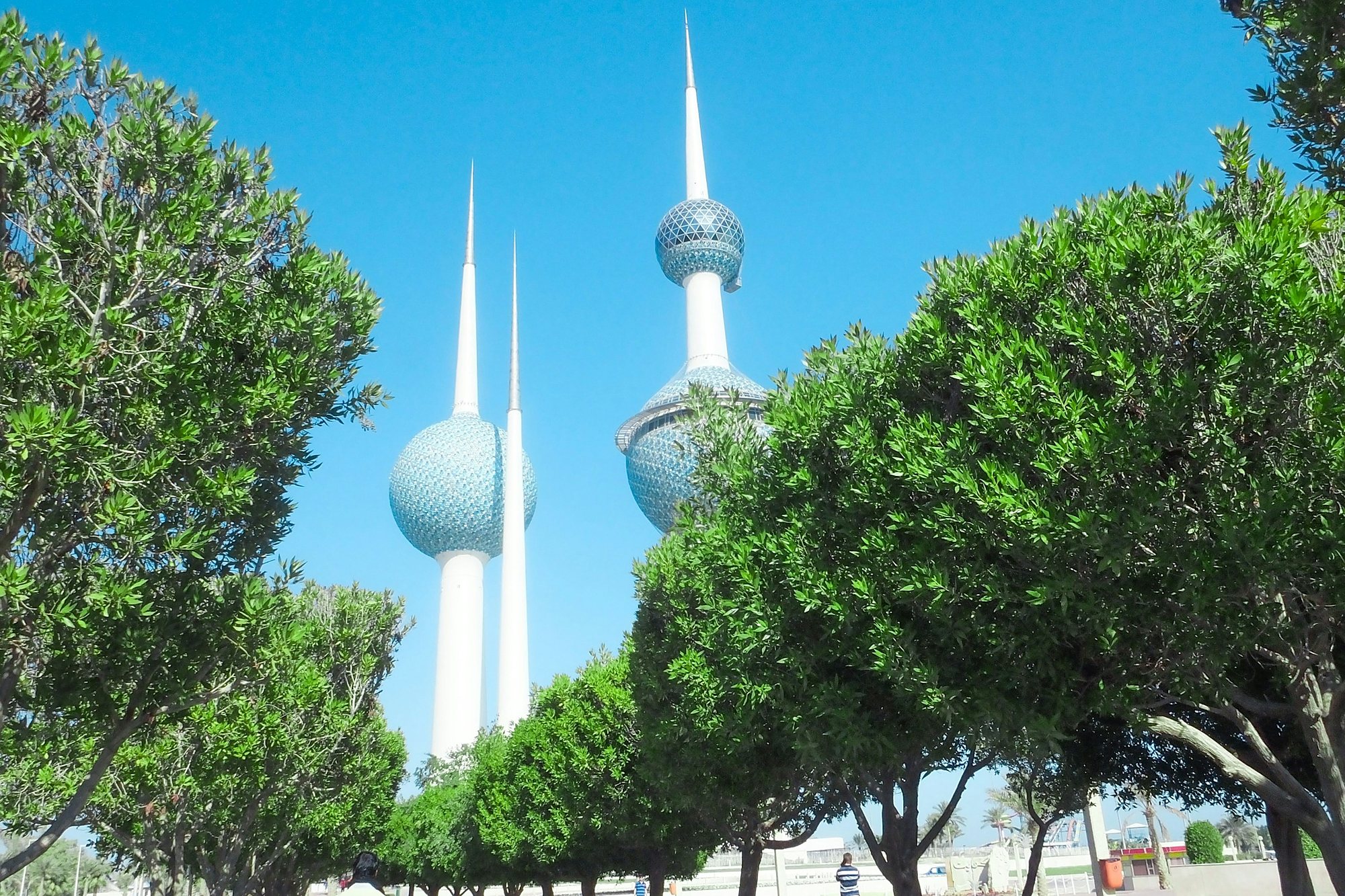 The Kuwait Towers rising above a tree-lined walk