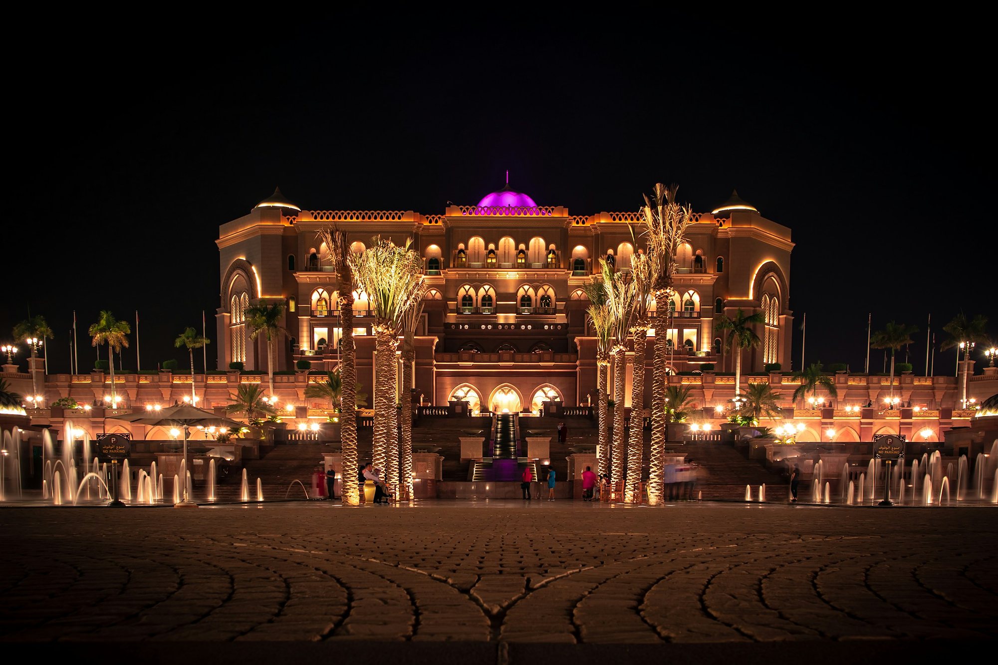 Emirates Palace lit gold at night among palms and fountains, Abu Dhabi
