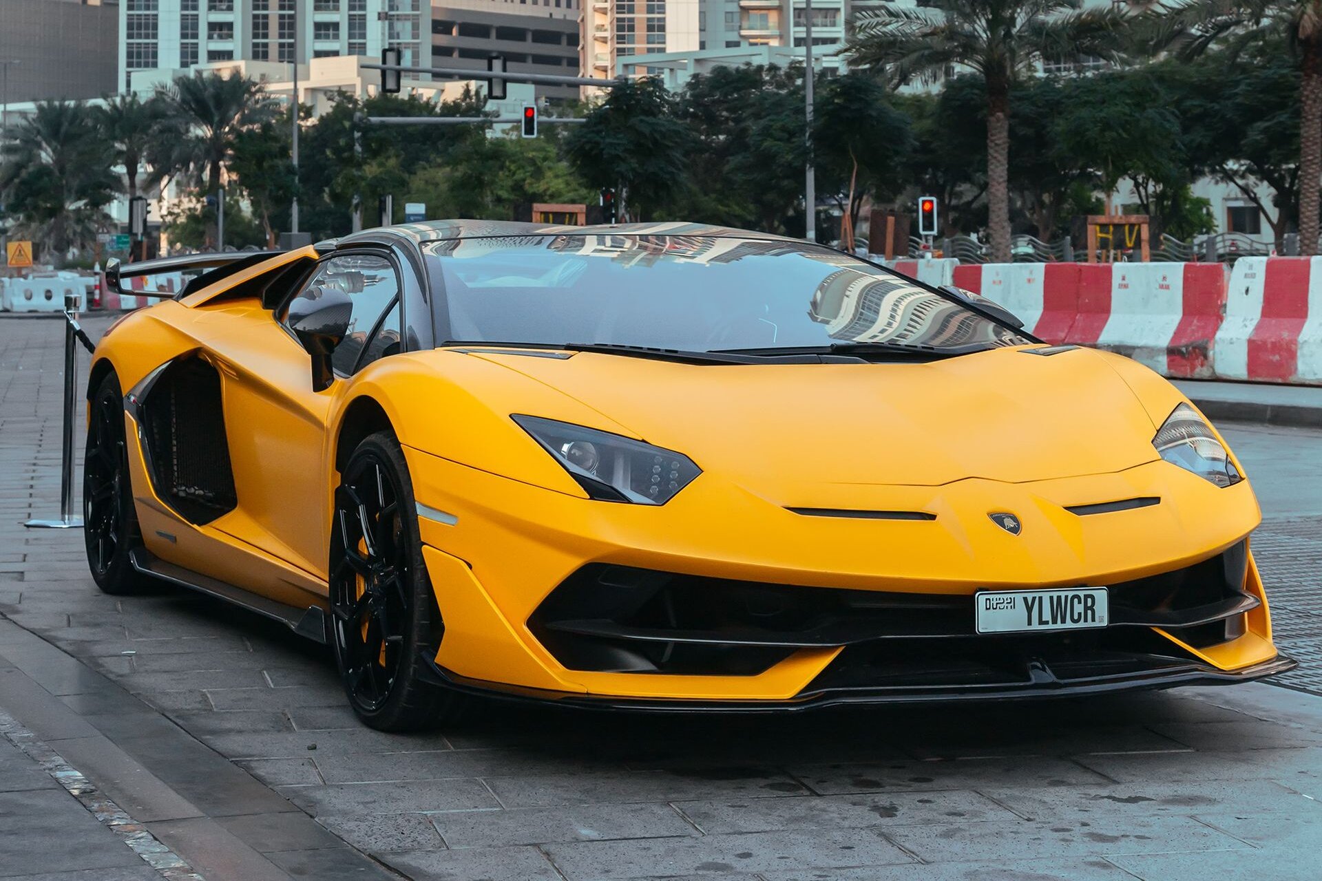 A yellow Lamborghini Aventador with Dubai plates below the towers