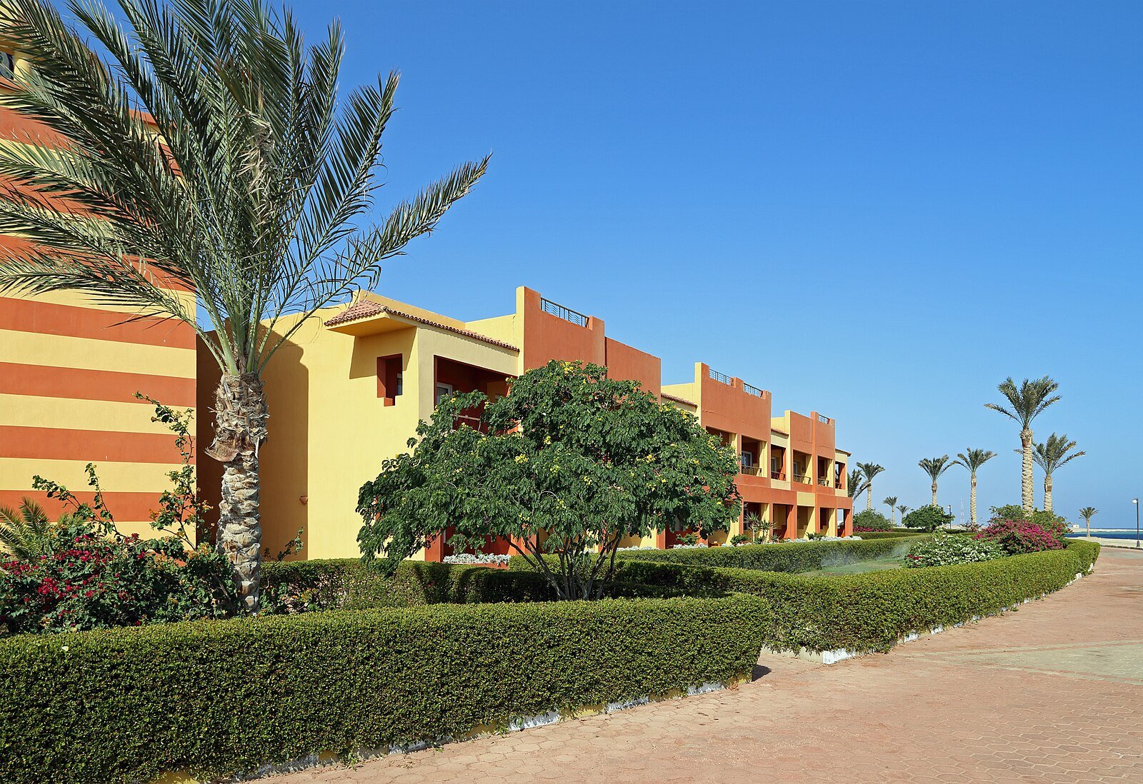 Palm-shaded gardens and the ochre-striped buildings of a beach resort at Abu Dabbab, Marsa Alam.