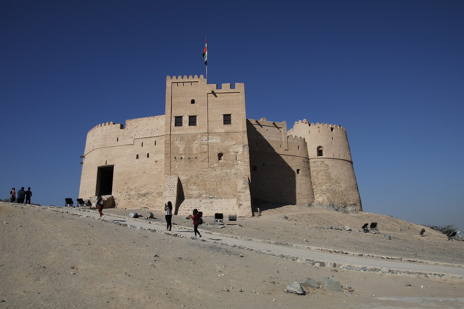 The stone towers of Fujairah Fort, seat of the ruling family's forebears, standing against a deep blue sky.