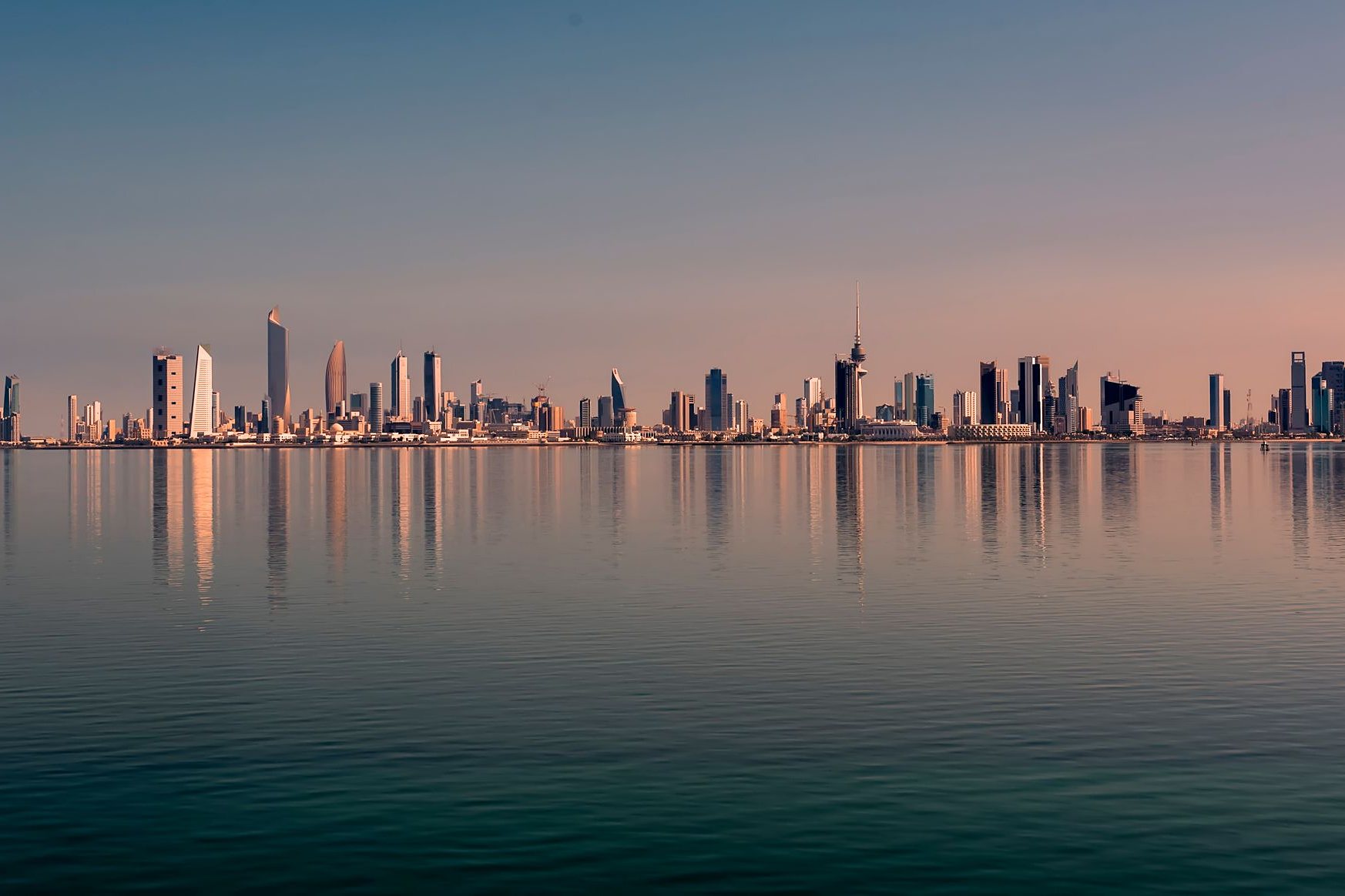 The Kuwait City skyline reflected in the calm Gulf at dawn