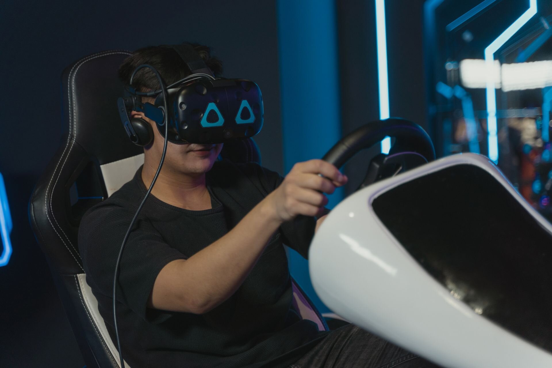A gamer in a VR headset at the wheel of a racing simulator