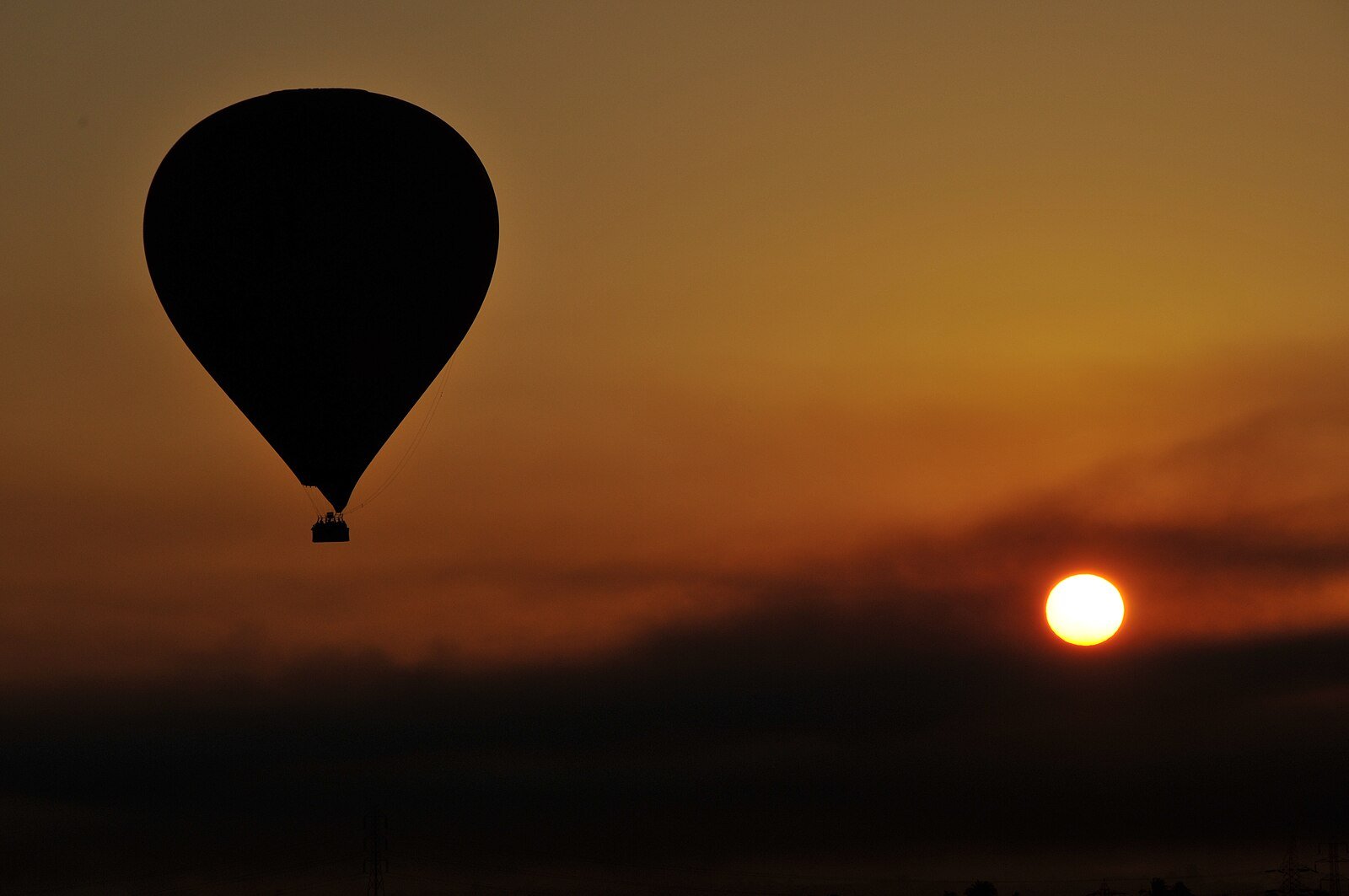 A hot air balloon silhouetted against a glowing sunrise over the West Bank of Luxor, Egypt.