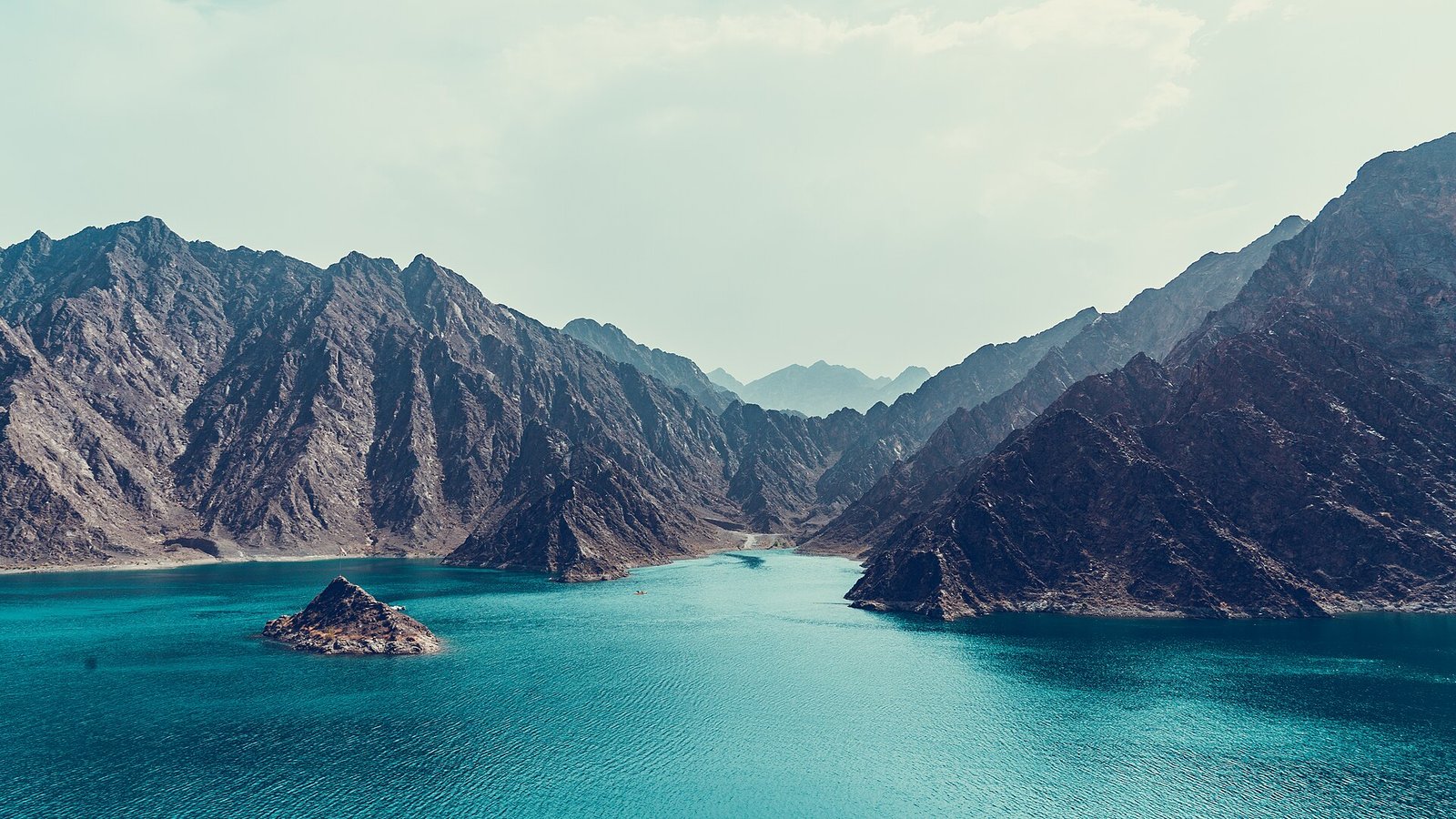 Turquoise water of Hatta Dam among the jagged Hajar Mountains, Dubai