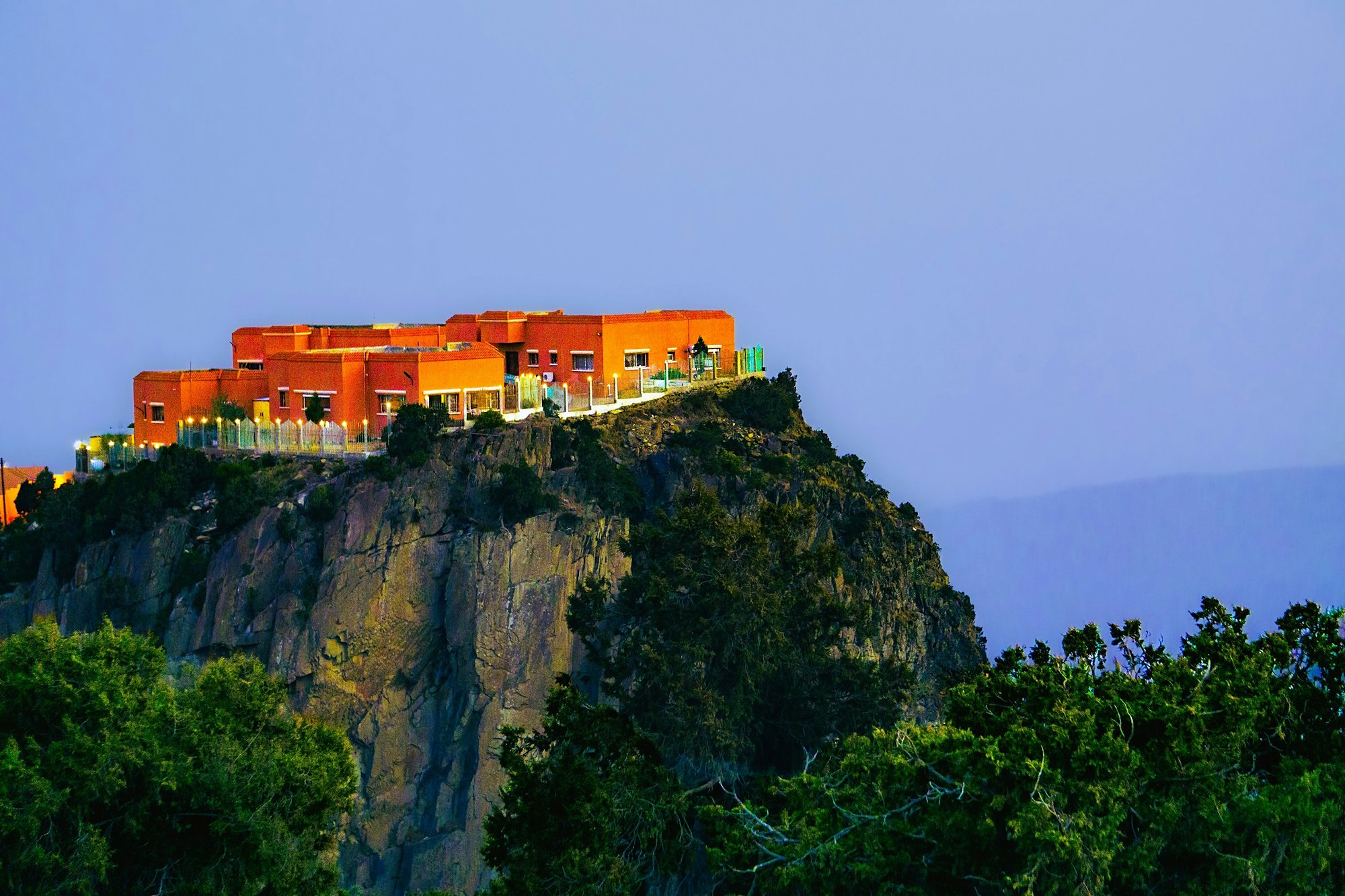 A cliff-top building above the green Asir mountains near Abha