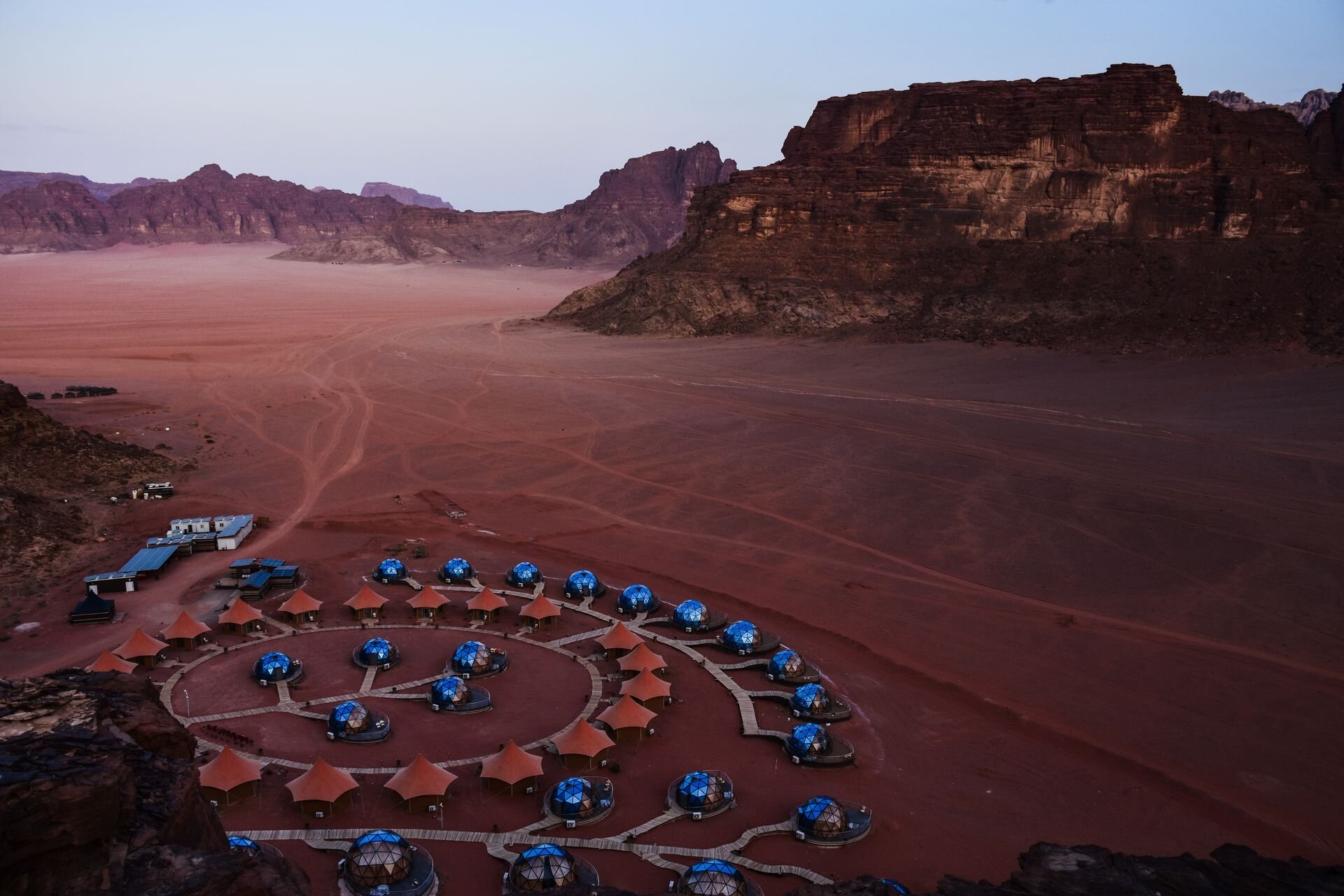 A ring of domes and tents in the red valley of Wadi Rum at dusk, Jordan