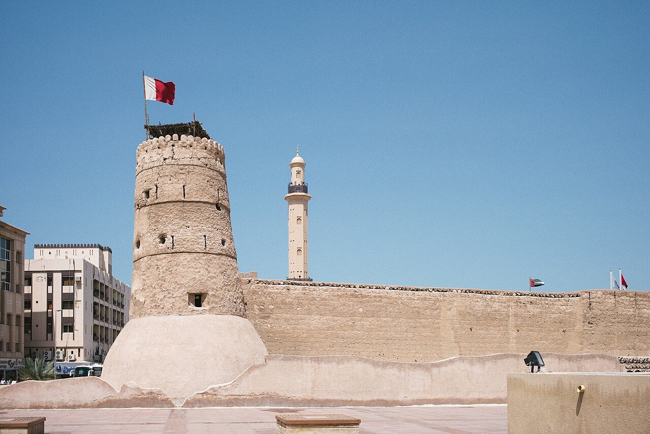 The round watchtower and walls of Al Fahidi Fort, home of the Dubai Museum, beneath a clear blue sky.