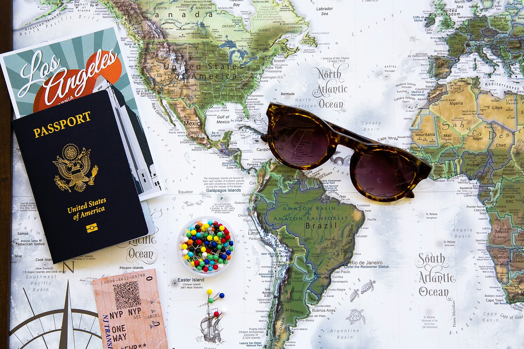A passport, a rail ticket and sunglasses laid out on a world map