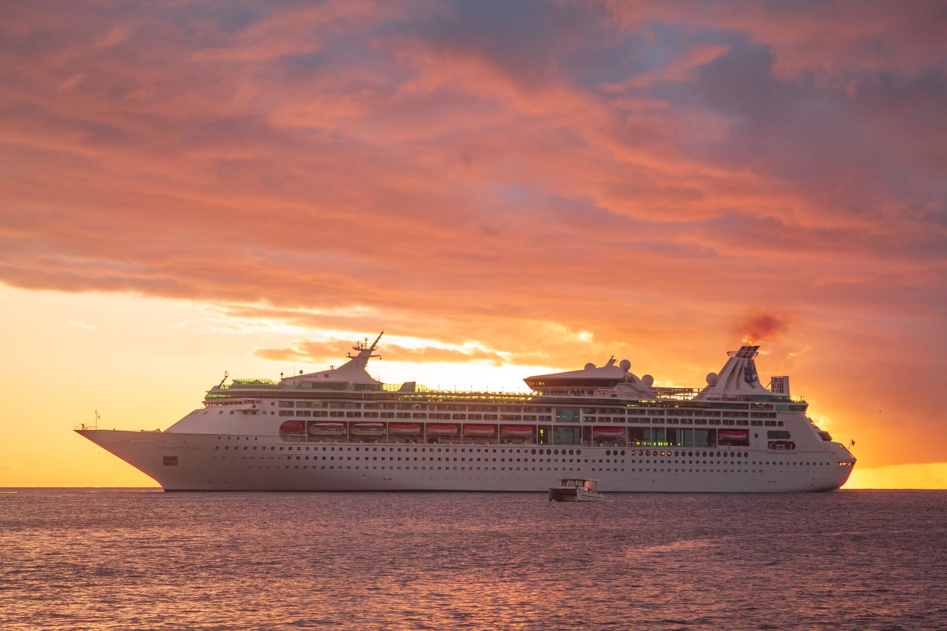 A cruise ship at anchor under a blazing sunset sky