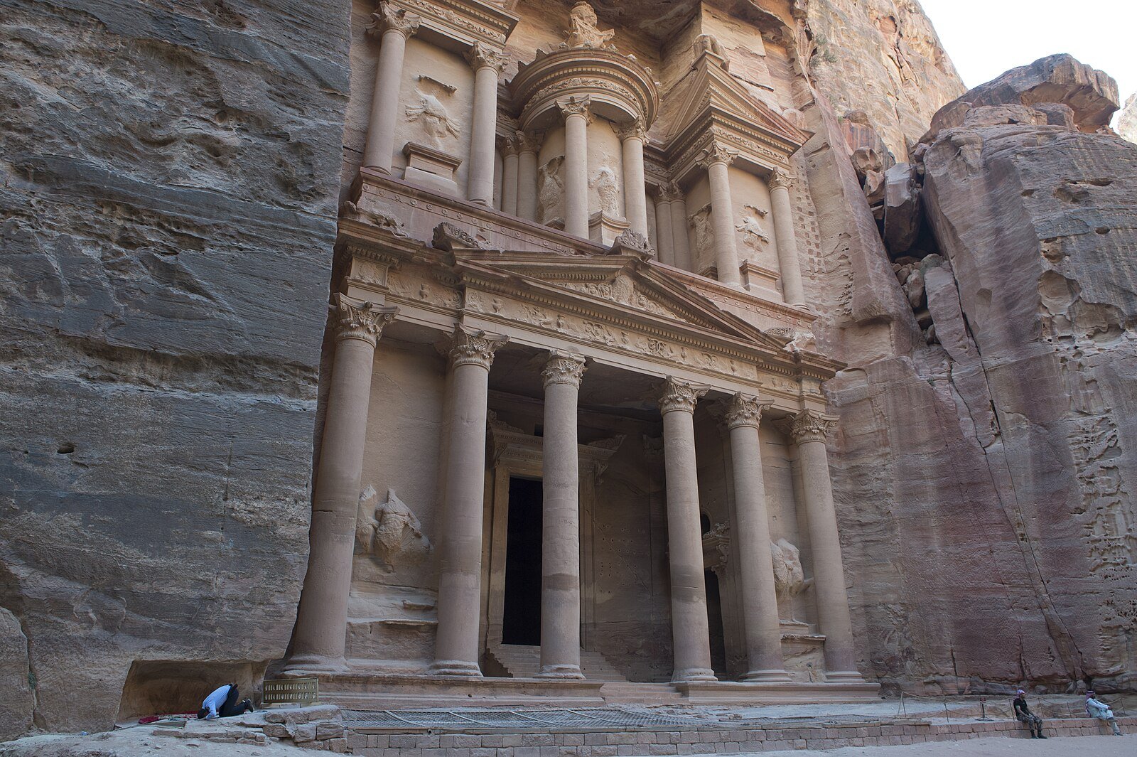 The rose-red facade of Al-Khazneh, the Treasury, framed by the sandstone walls of the Siq in Petra.