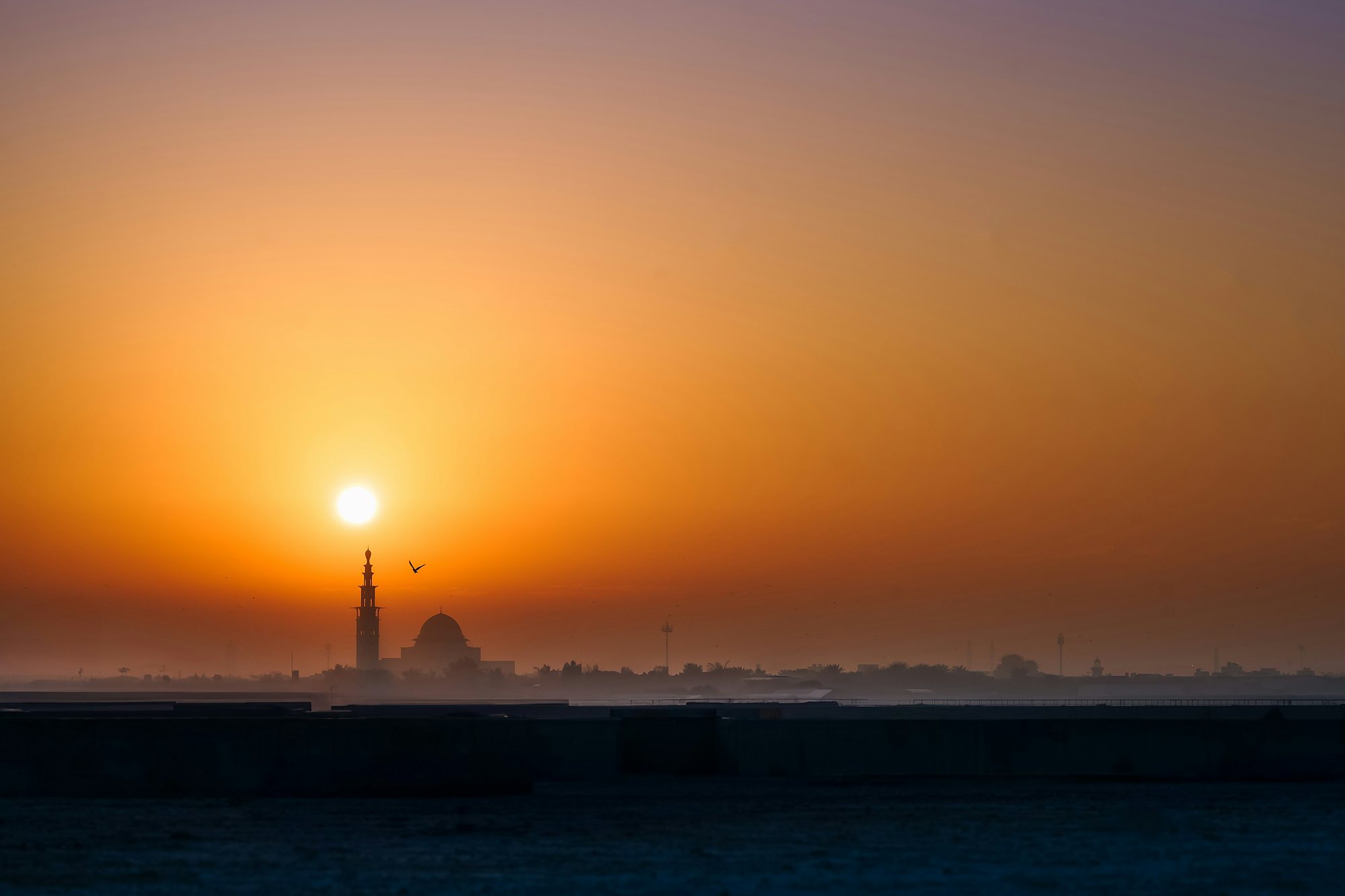A mosque silhouetted against the sunrise over Ajman