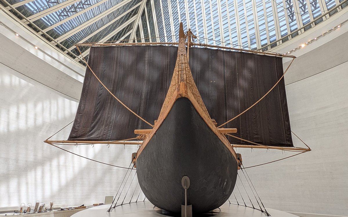 A reconstructed Bronze Age Magan boat, its dark sail spread wide, stands beneath the skylit roof of the Zayed National Museum.