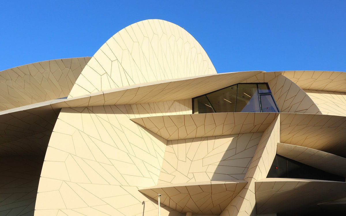 The interlocking desert-rose discs of the National Museum of Qatar rise against a clear blue Doha sky.