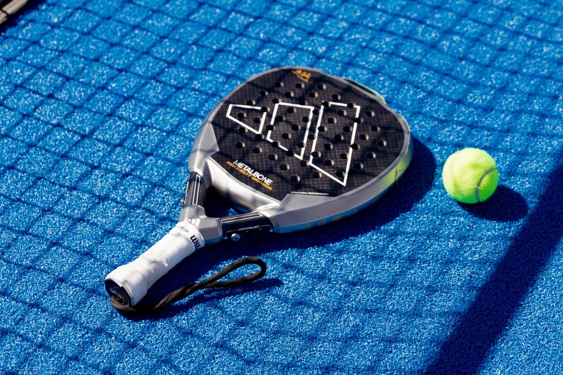 A padel racket and ball on a blue court