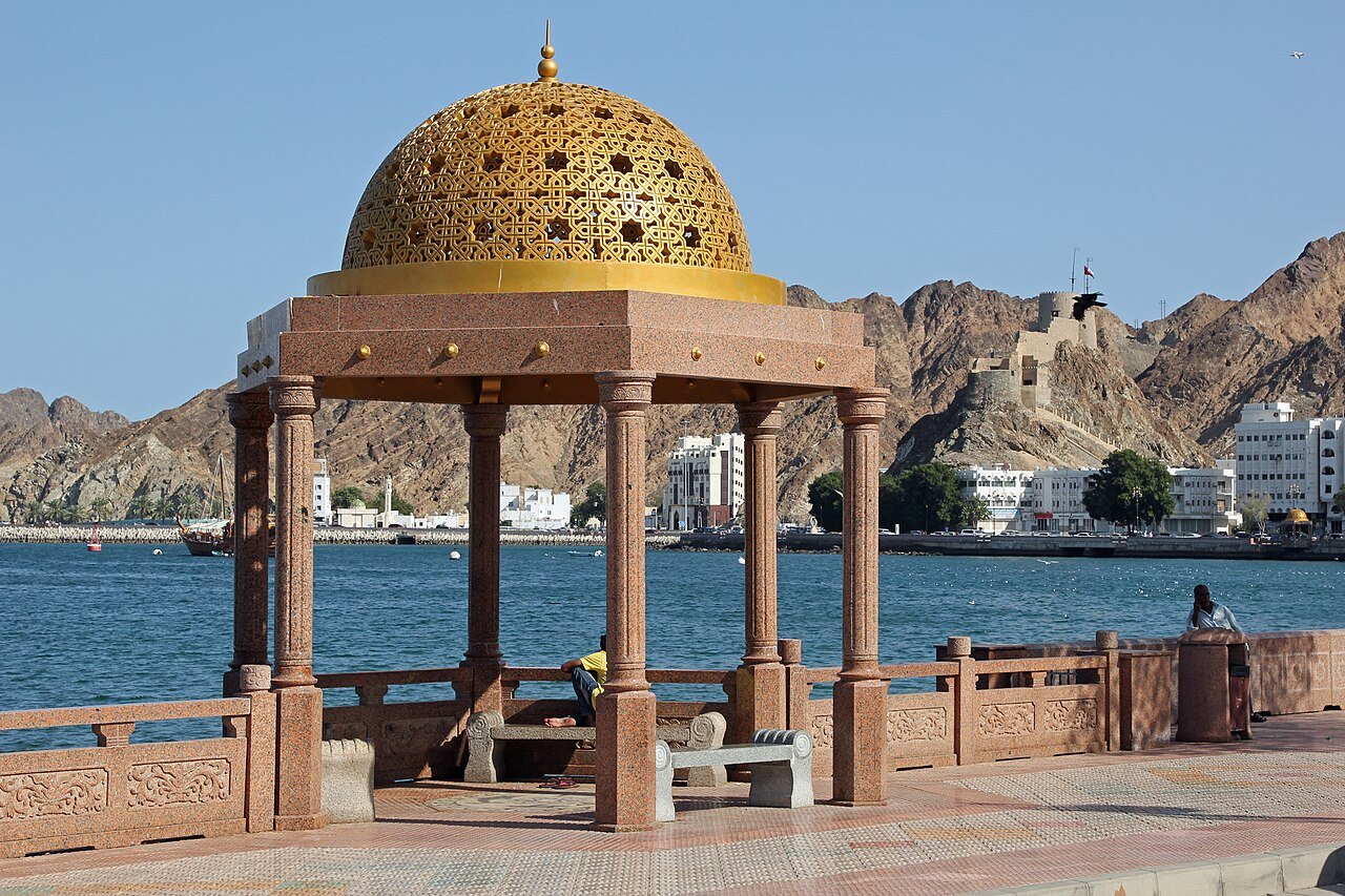 A gilded domed pavilion on the Muttrah Corniche in Muscat, the harbour and mountains beyond.