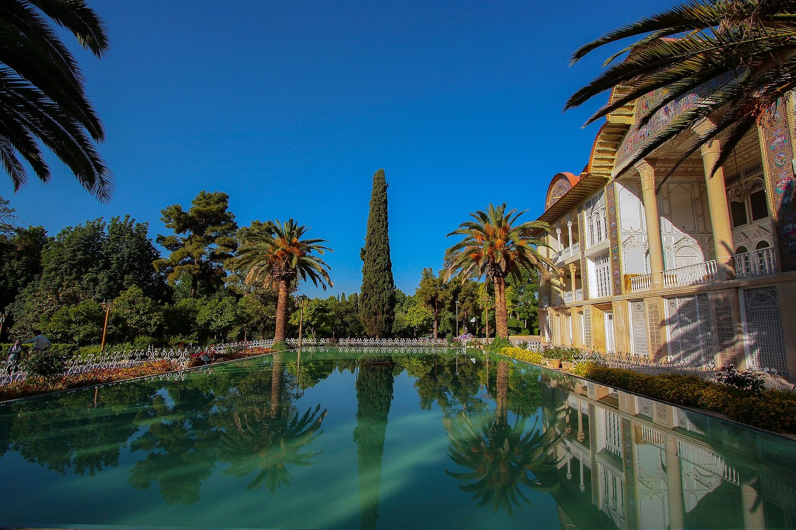 The Qavam pavilion of Eram Garden in Shiraz reflected in its long pool among palms and cypresses