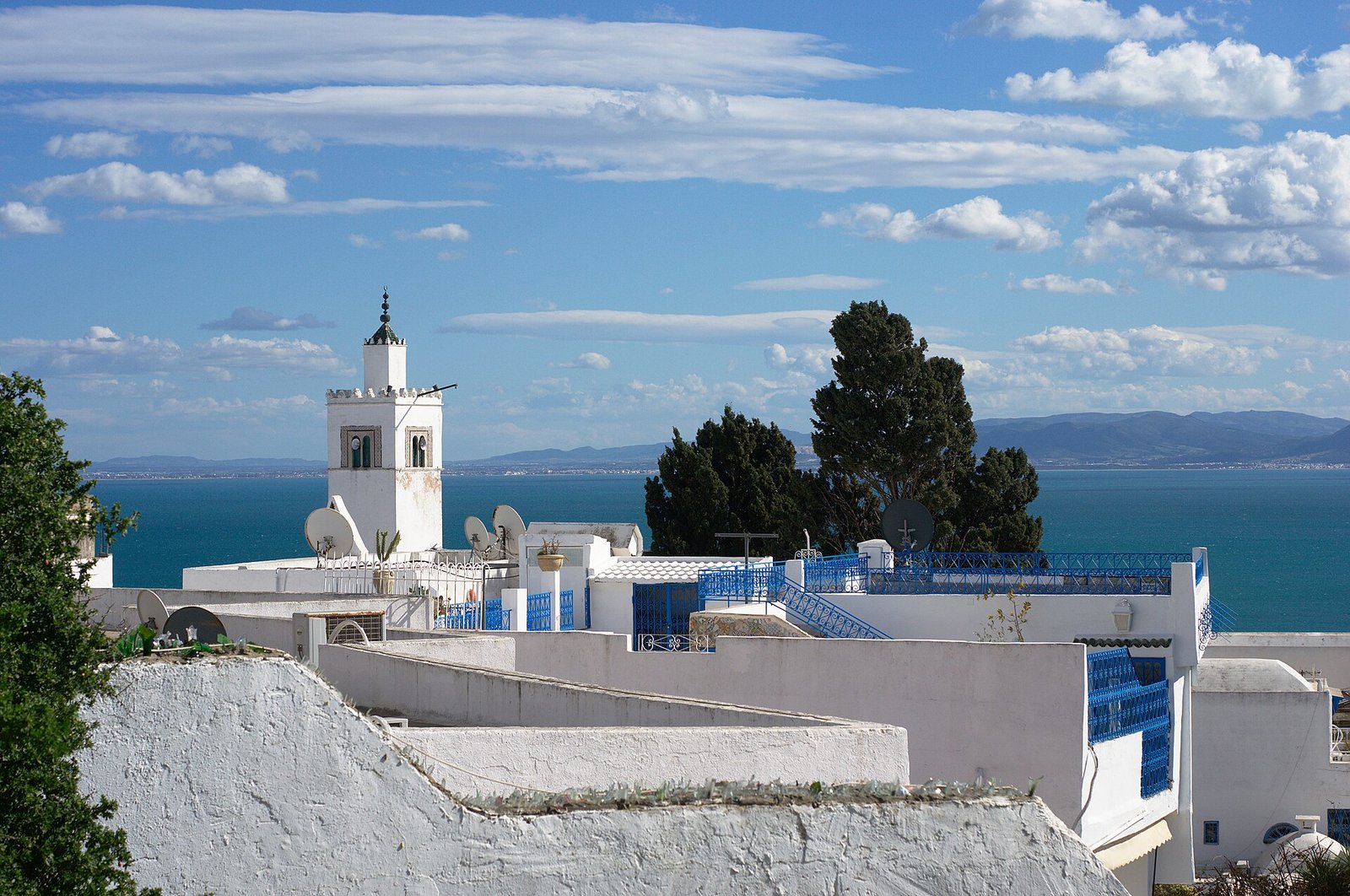 White houses with blue shutters and a slender minaret above the Gulf of Tunis at Sidi Bou Said.
