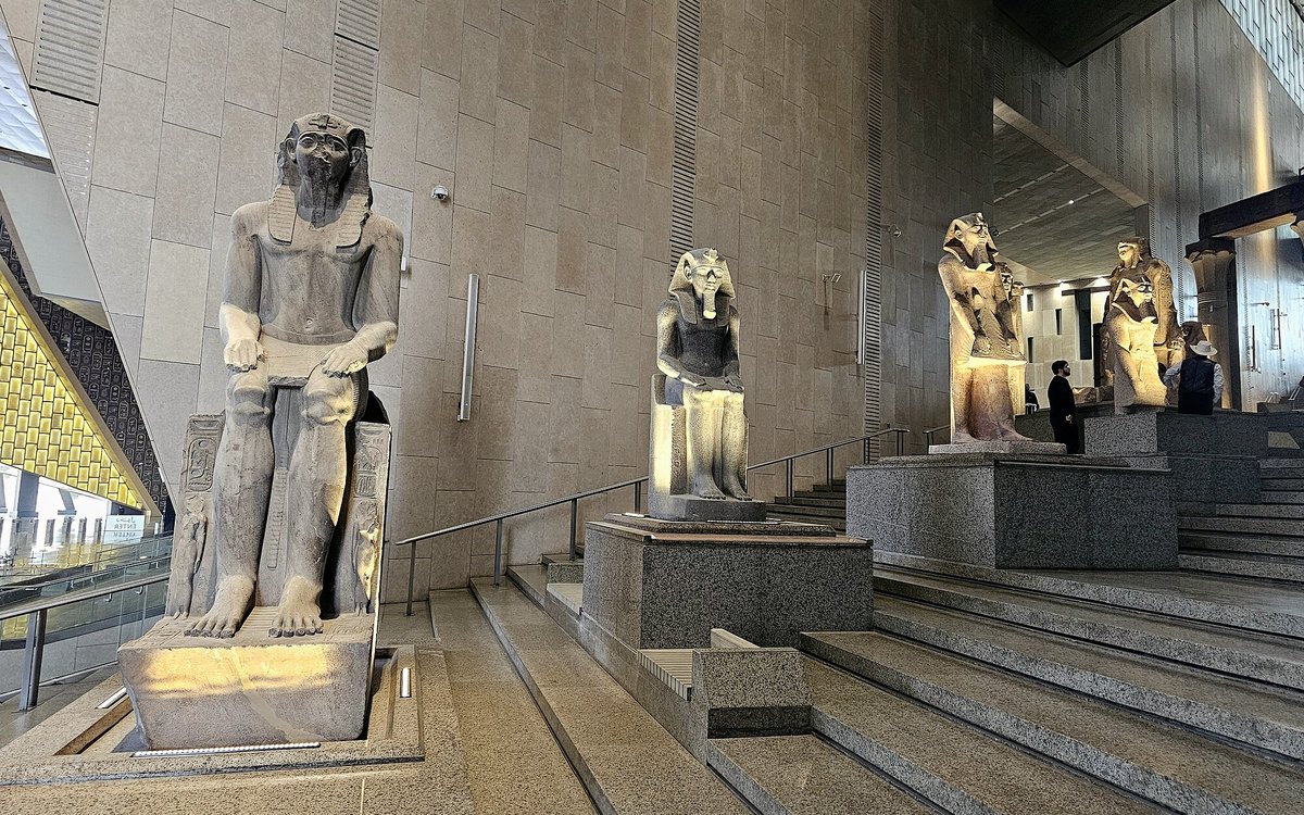 Colossal pharaonic statues line the Grand Staircase of the Grand Egyptian Museum in Giza.