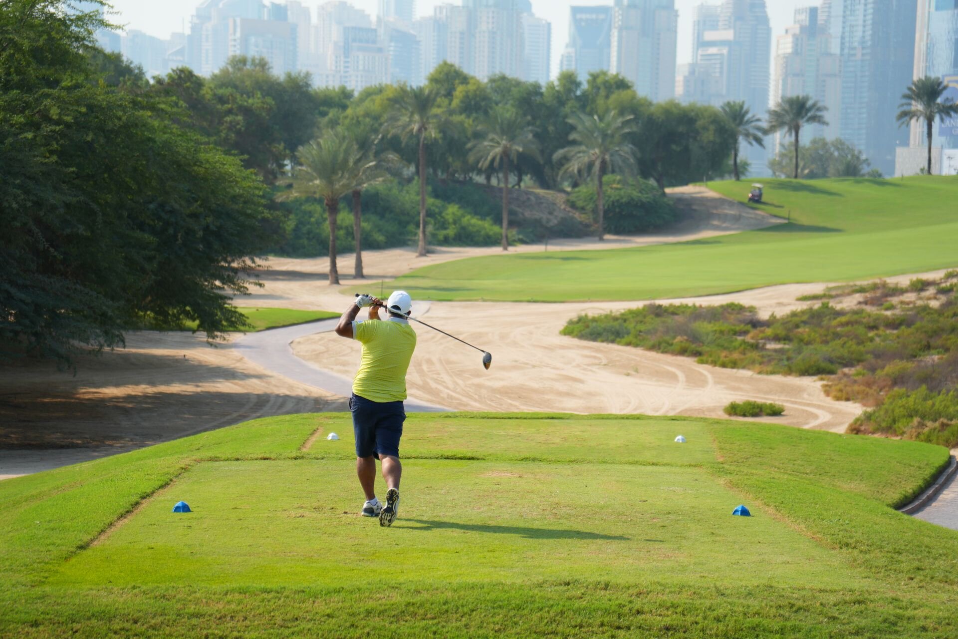 Teeing off among palms and desert sand, with the towers of Dubai behind