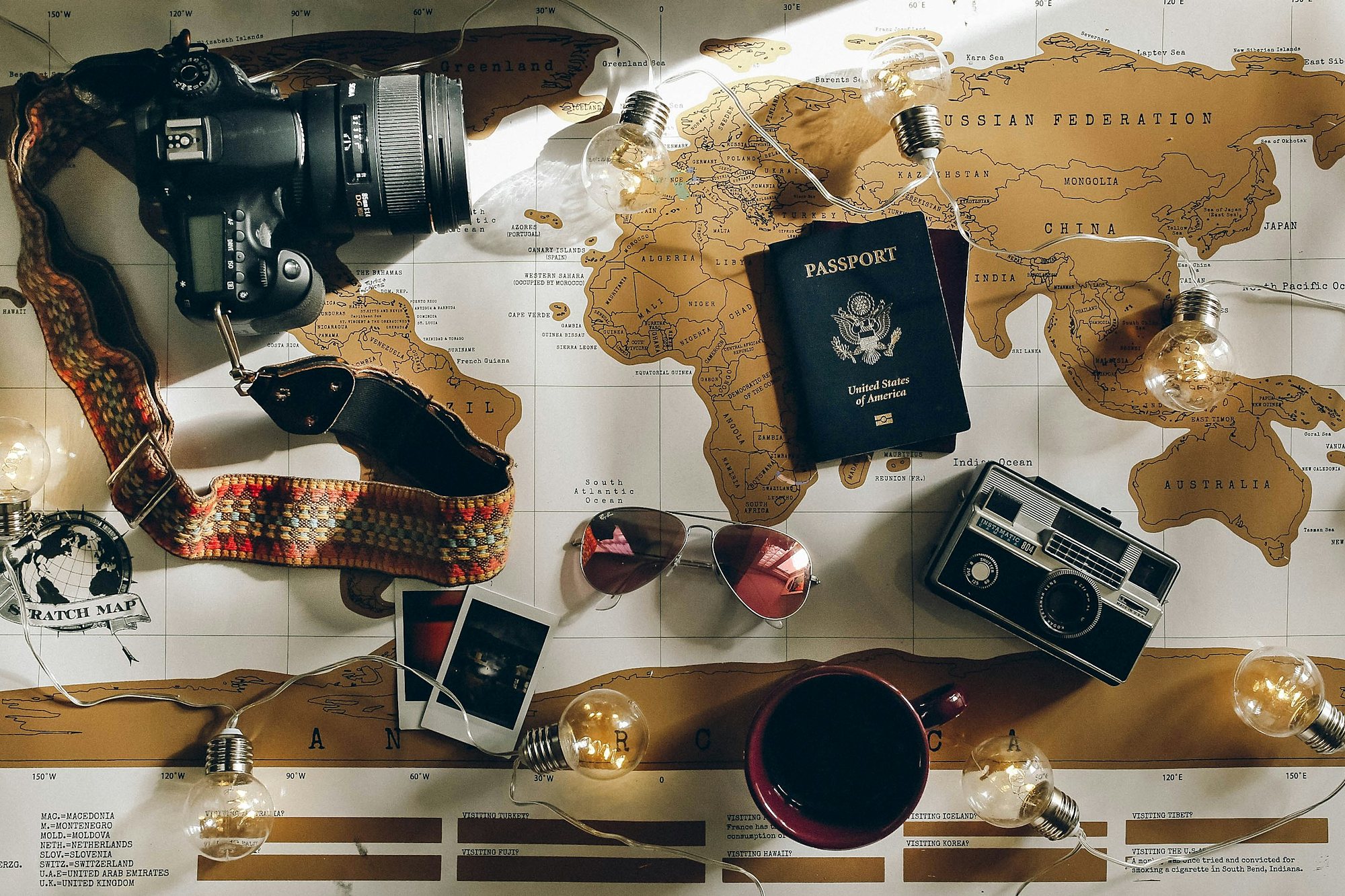 A passport, cameras and sunglasses laid out on a world map