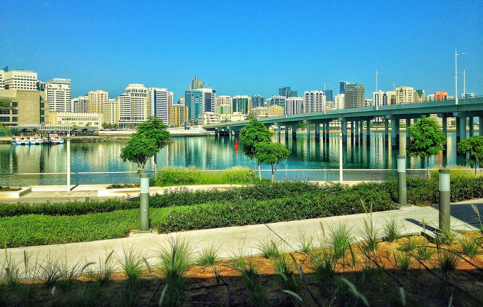 The landscaped waterfront promenade of Al Maryah Island, Abu Dhabi's financial and startup hub, looking across the channel to the city.