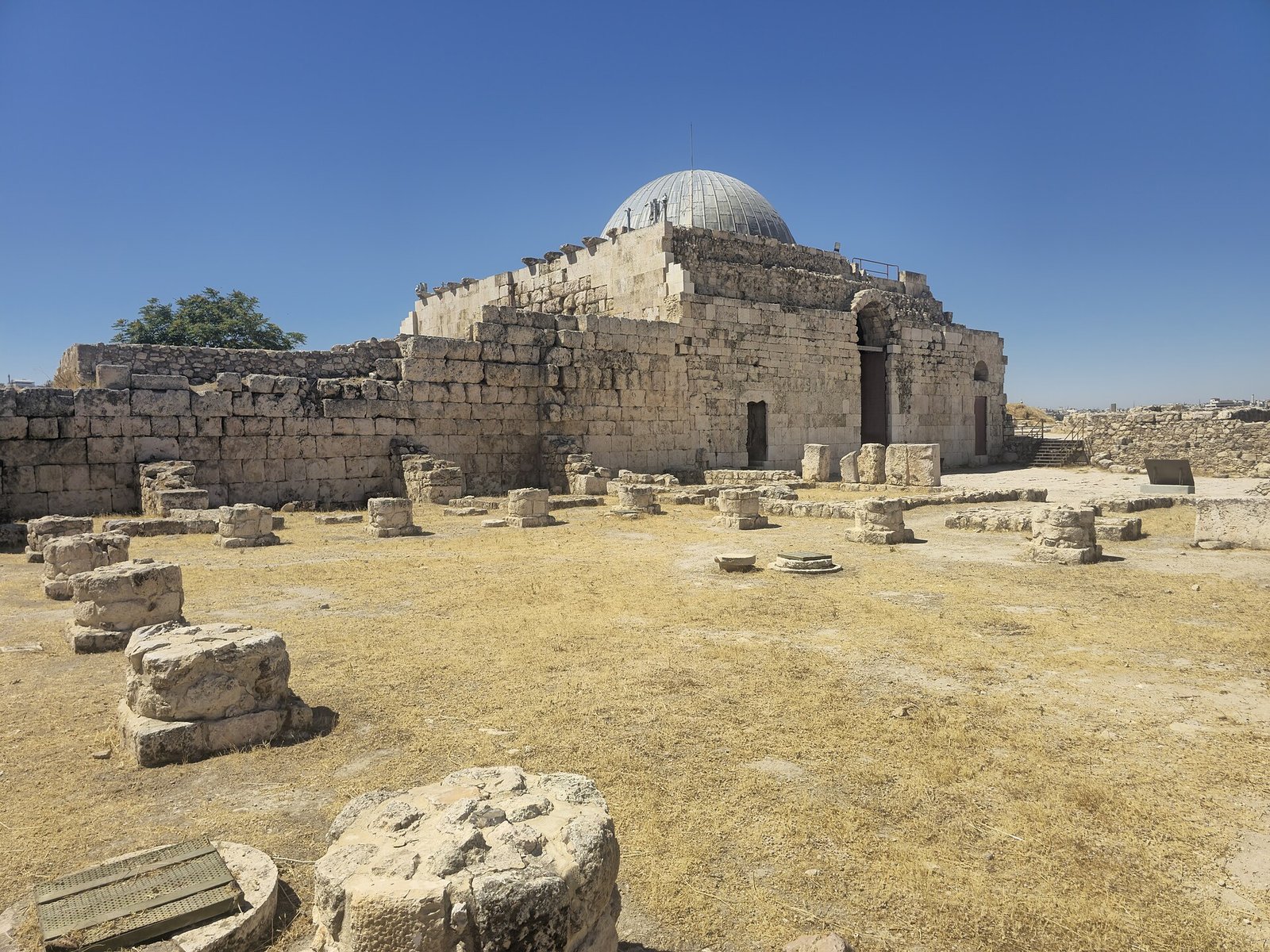The domed Umayyad Palace audience hall rising above the ancient stones of the Amman Citadel under a clear blue sky.