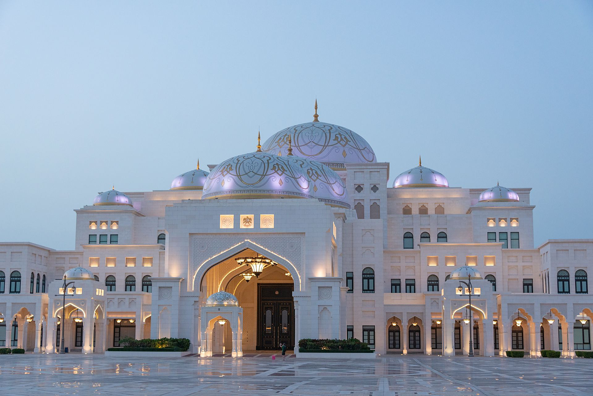 The white domes and grand arched entrance of Qasr Al Watan lit softly at dusk