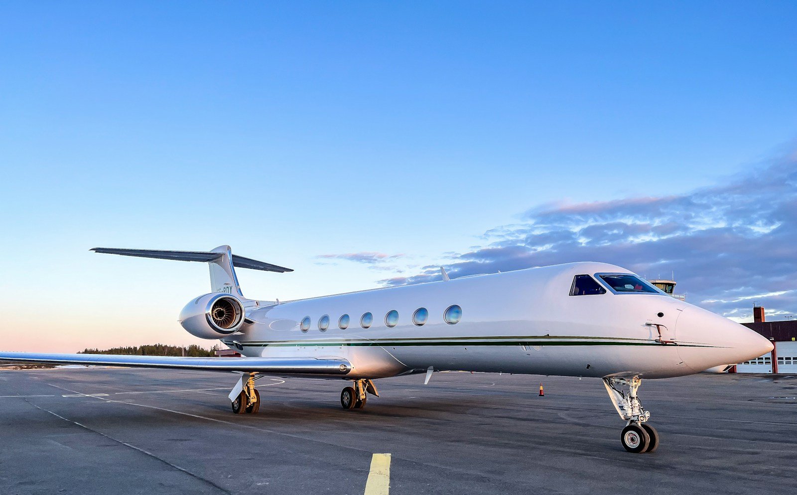 A white Gulfstream business jet waits on the apron beneath a soft evening sky.
