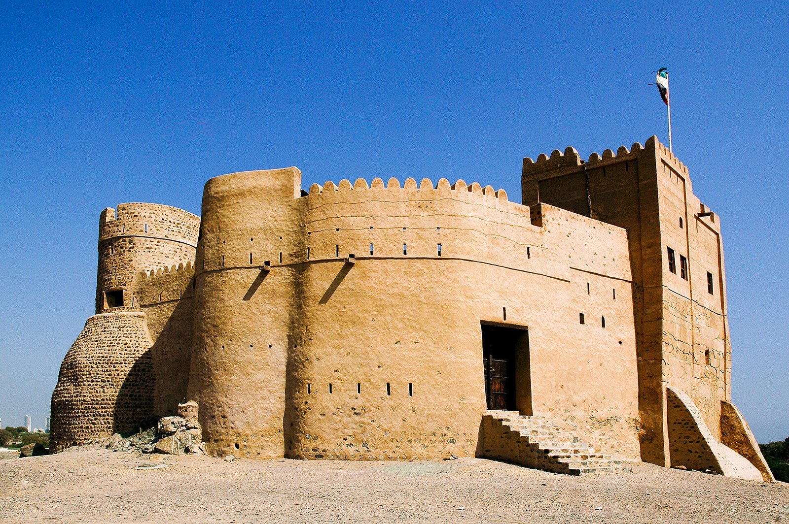 The restored towers and walls of Fujairah Fort under a deep blue sky