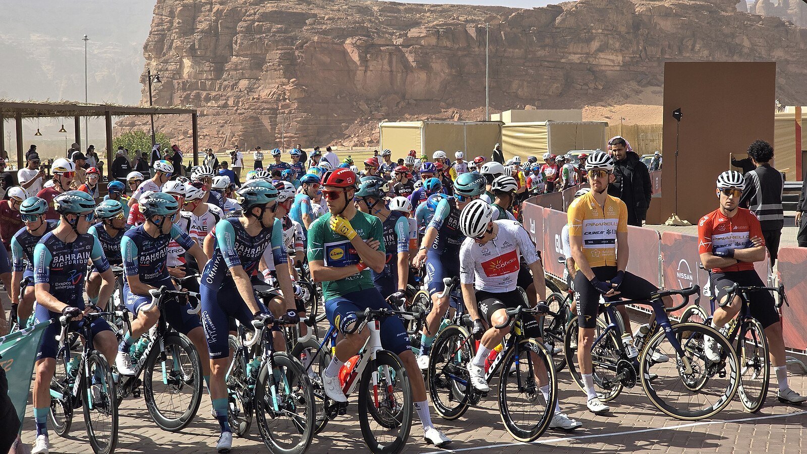 The peloton gathered at the start of a stage of the AlUla Tour, beneath the sandstone cliffs of AlUla.