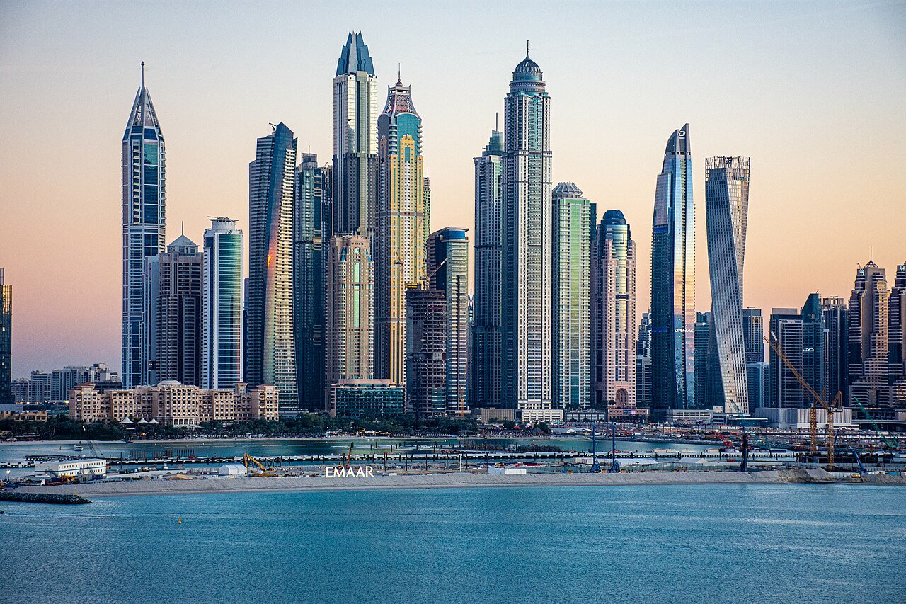 The residential towers of Dubai Marina glowing at dusk above the water.